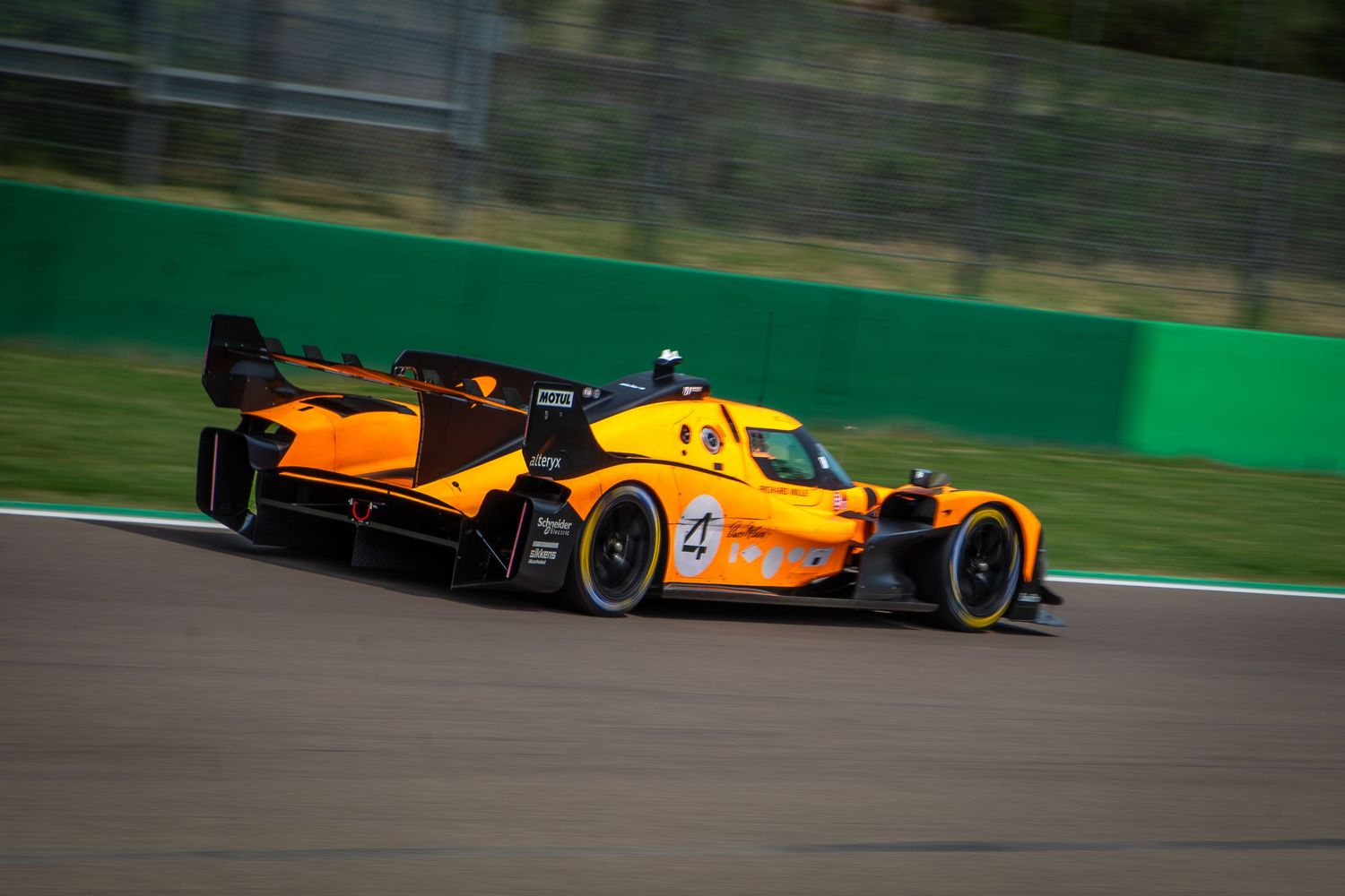 Side profile tracking shot of the McLaren Hypercar speeding down the asphalt with motion blur.