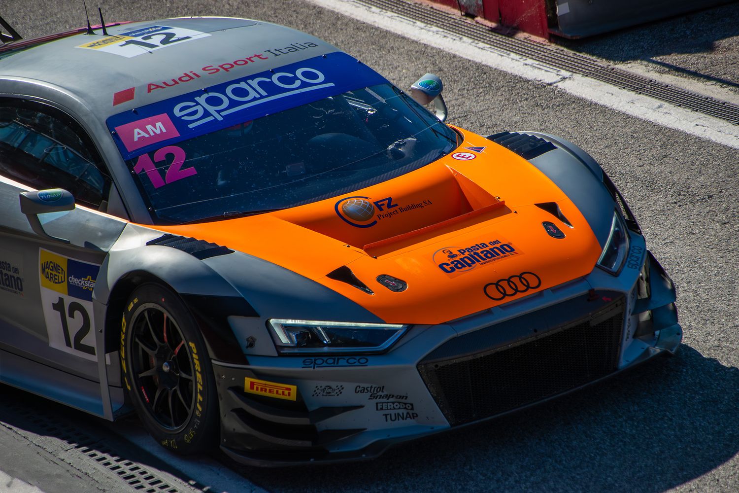 High-angle close-up of a grey and orange Audi GT3 car moving through the pit lane at Imola.