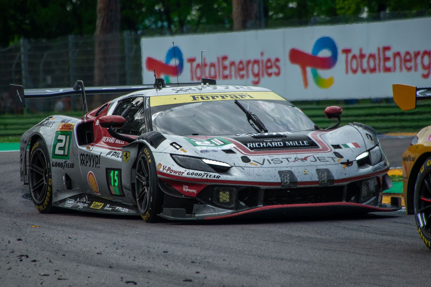 Battle scarred, silver and red Ferrari 296 GT3 racing car cornering at Imola.