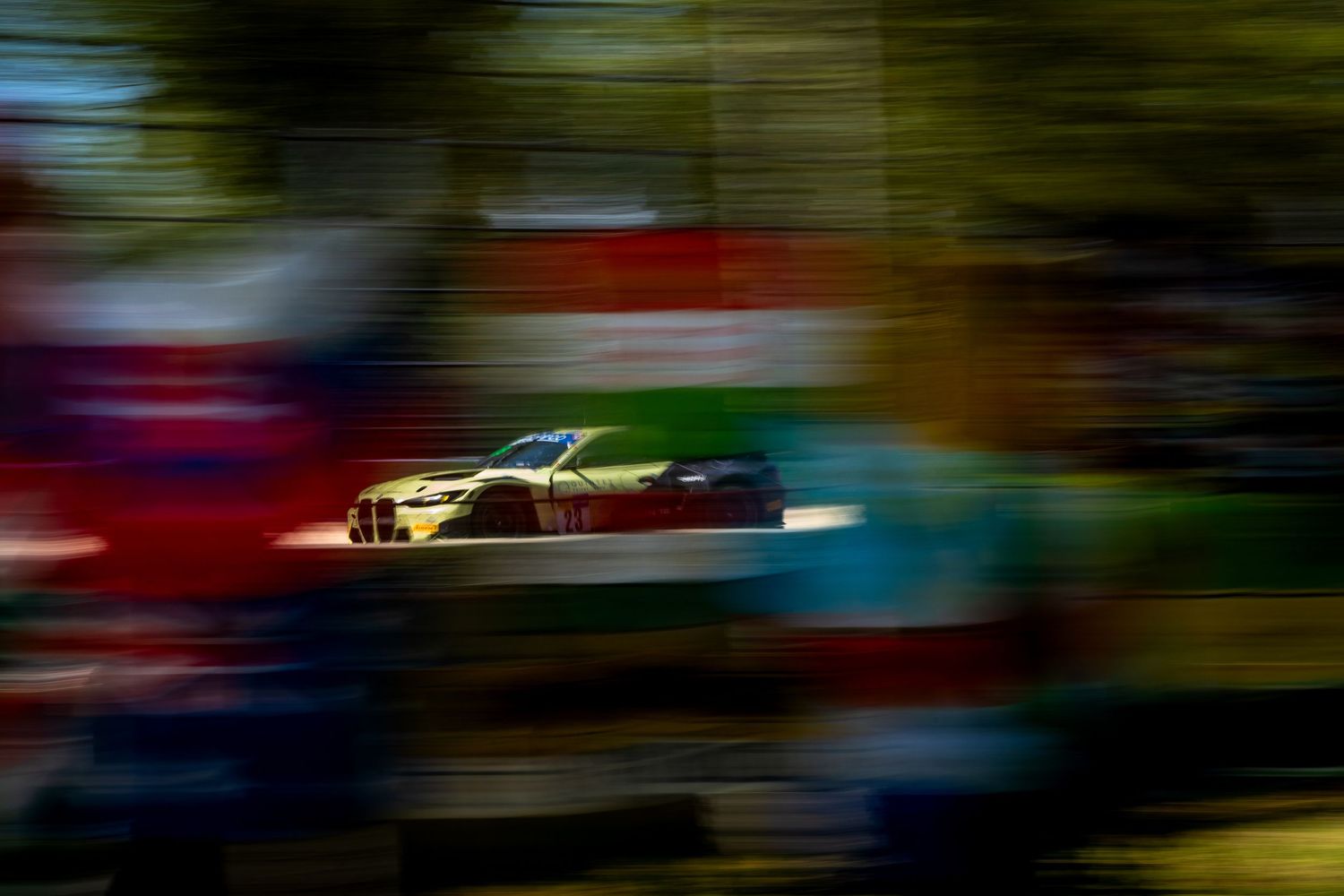 A GT race car speeds past the barriers in a dramatic panning shot at Imola.