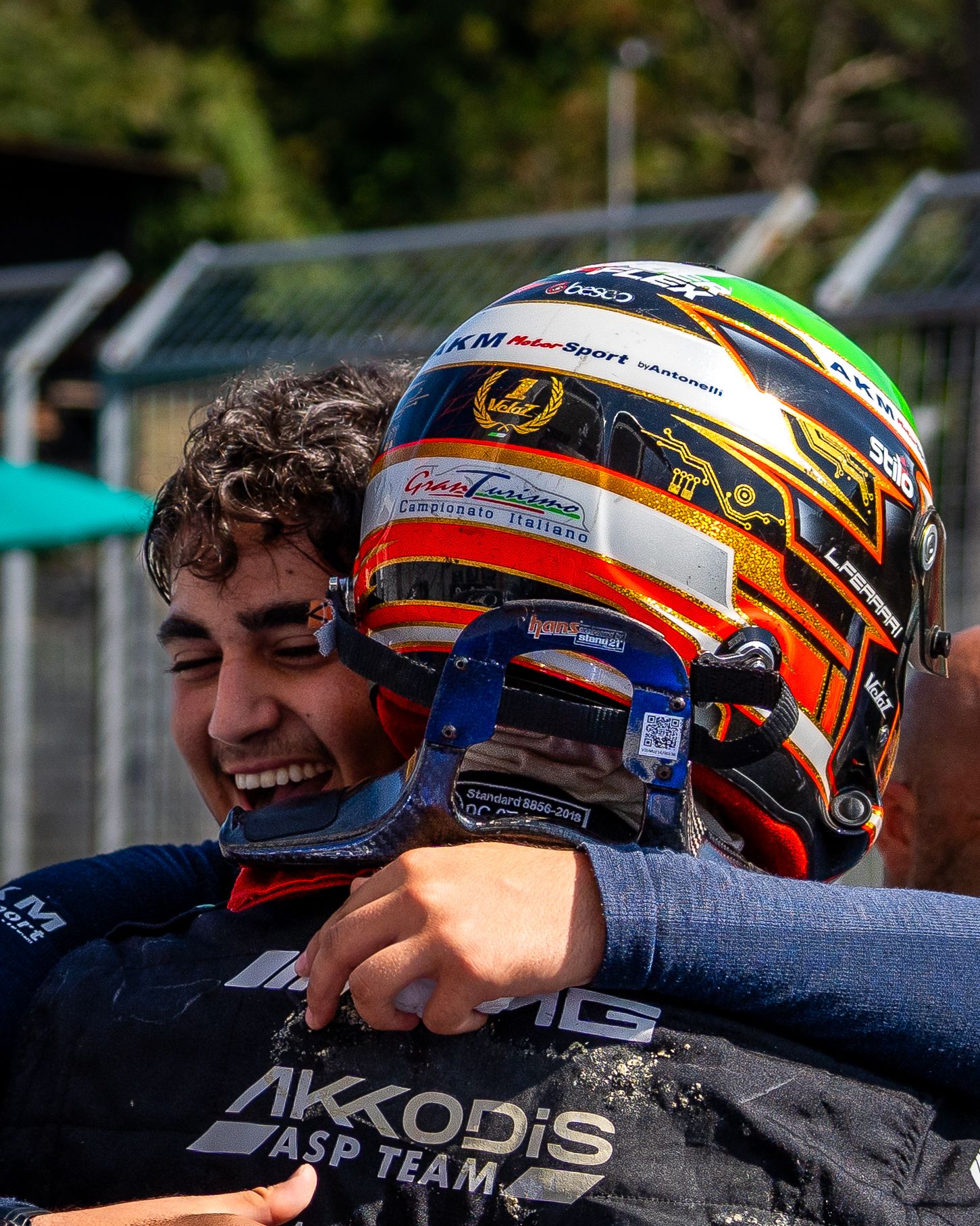 A young driver celebrating with a teammate, captured in an emotional post-race embrace.