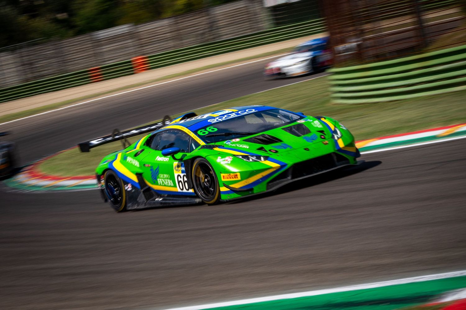 Green Lamborghini GT3 racing through a corner at Imola with a sharp panning shot.