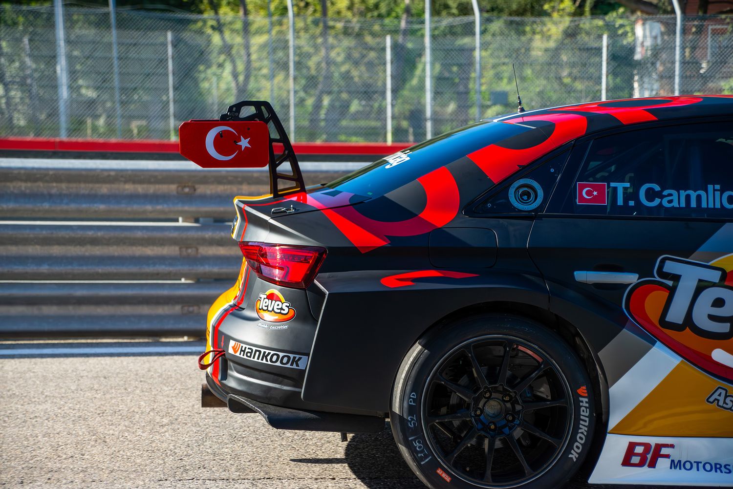 Close-up of the rear wing and wheel of a black and red Audi TCR car with the Turkish flag.