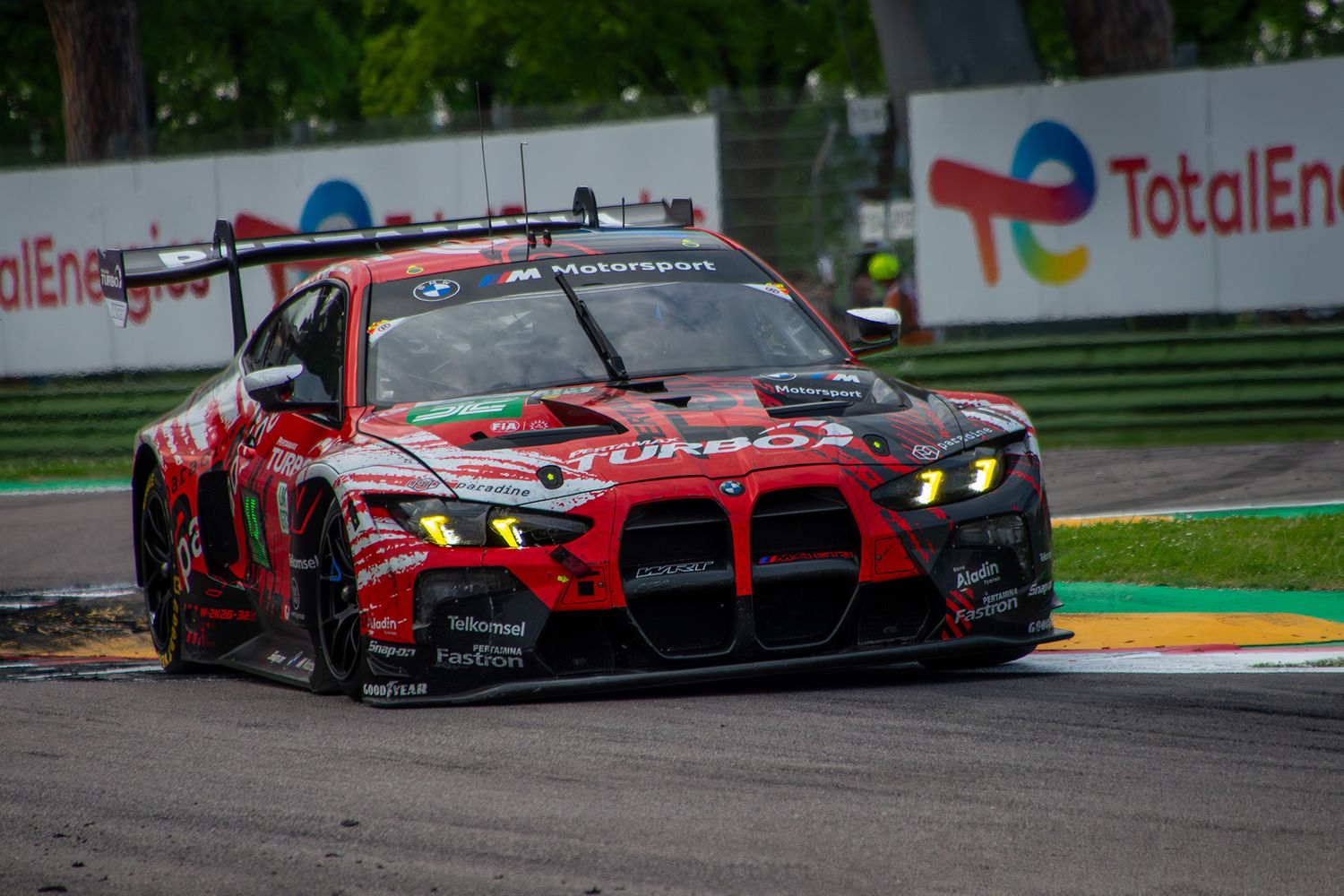 Red and black BMW M4 GT3 race car cornering at Imola.