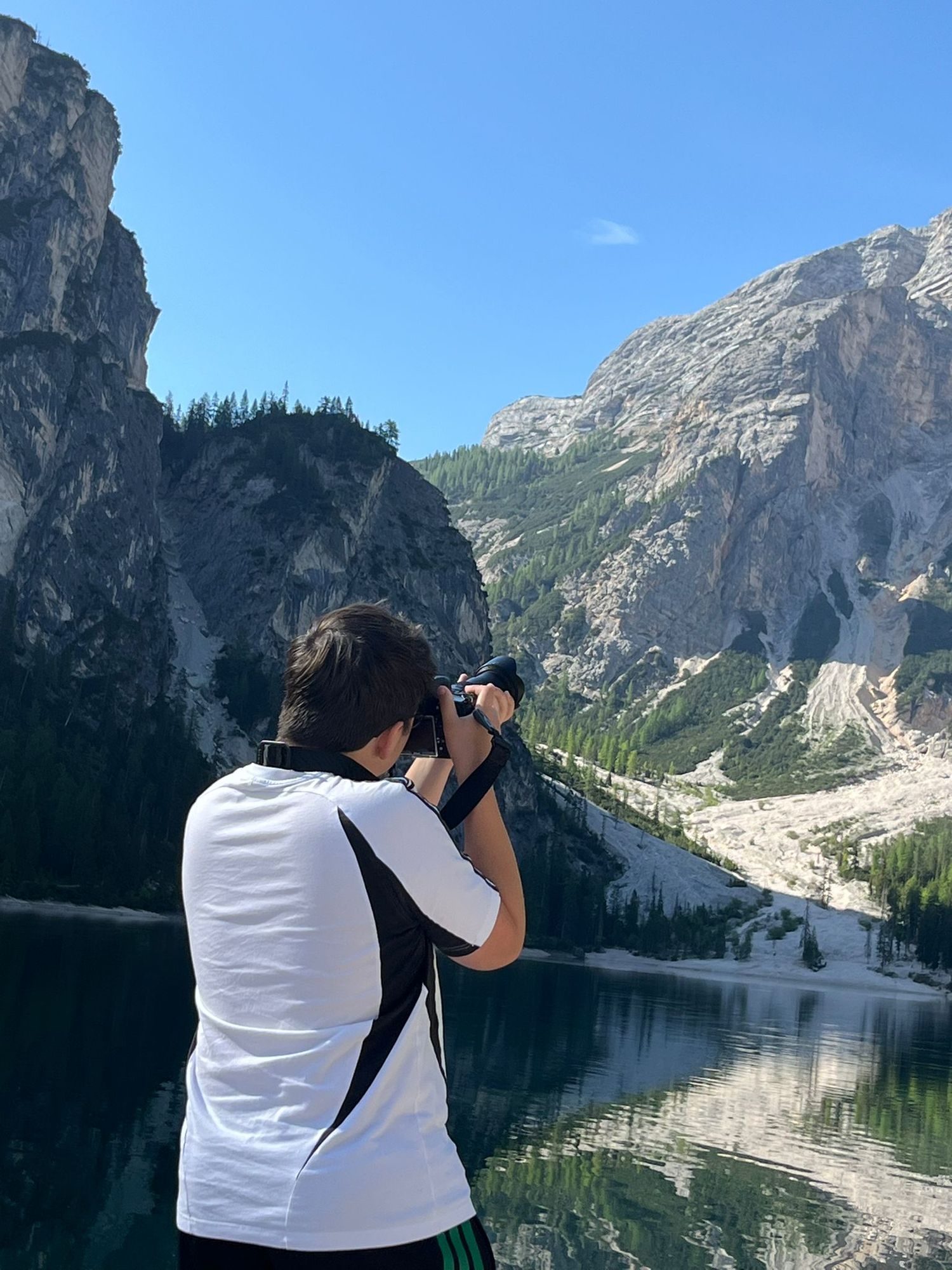 Motorsport photographer Nicolas Nyeste from behind, shooting a scenic mountain lake landscape.