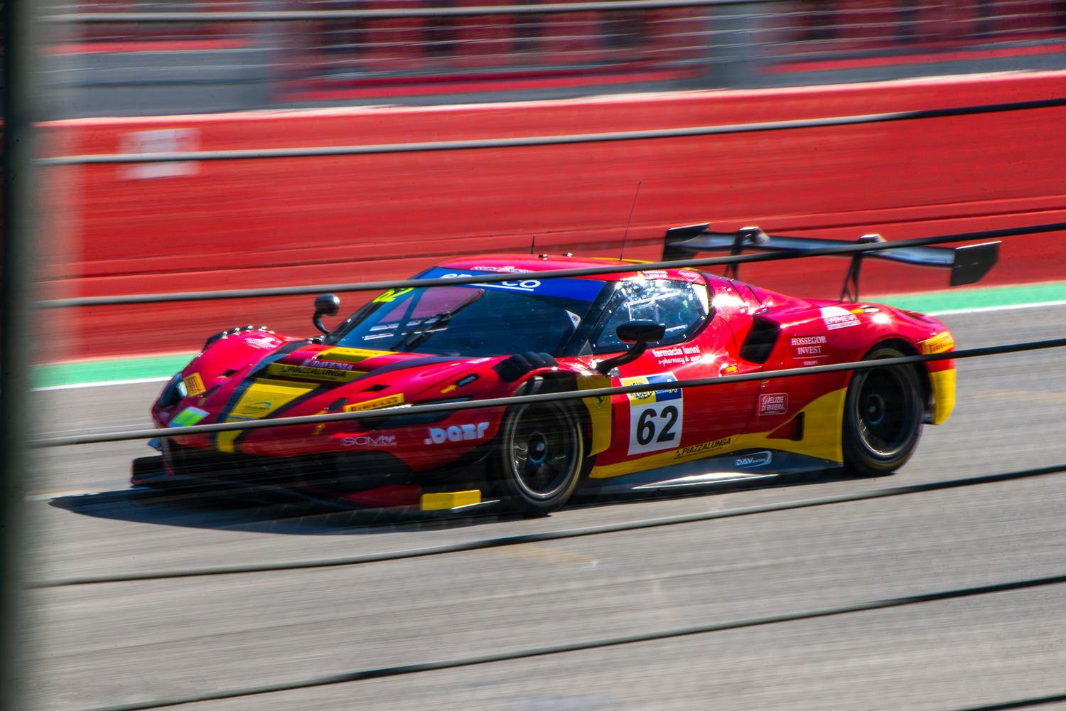 Red and yellow Ferrari 296 GT3 racing car speeding on track during the ACI Racing Weekend.