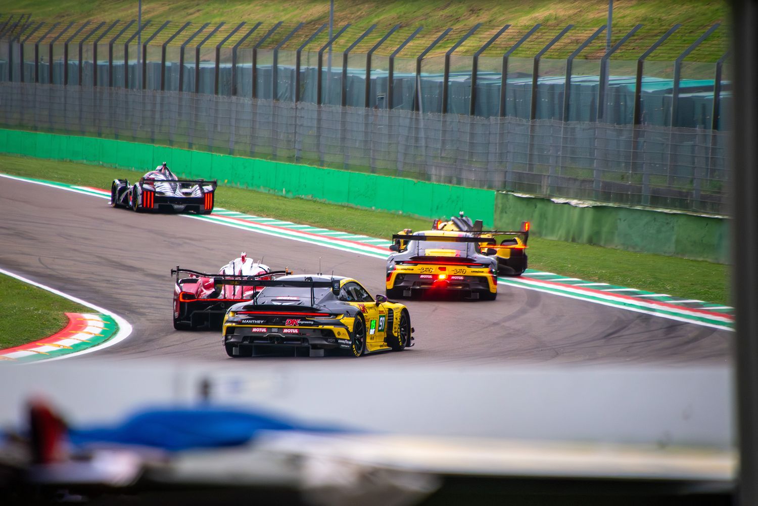 A pack of several endurance race cars driving away into a corner at Imola.