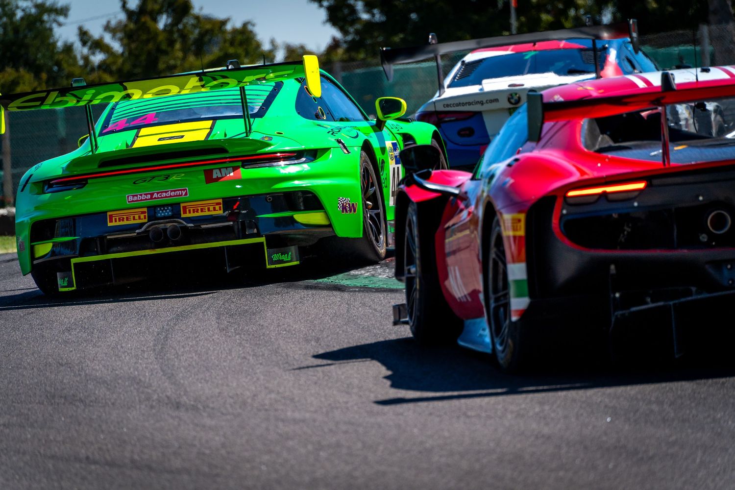 Green Porsche and red Ferrari GT3 cars battling closely through Imola.