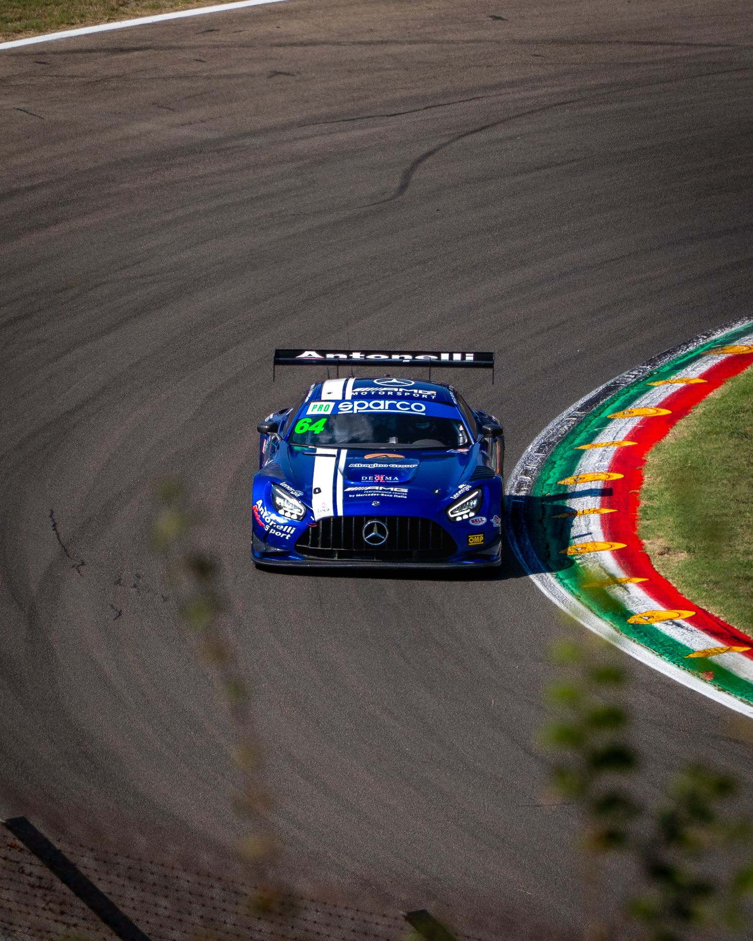 Blue GT3 race car navigating a sweeping corner at Imola, close to the red, white and green kerbs.