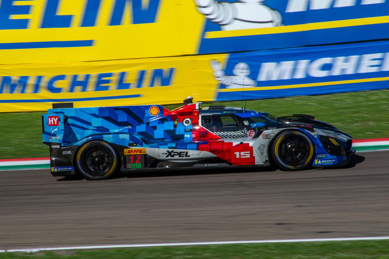 Blue and red BMW M Hypercar speeding along the track in front of a Michelin banner.
