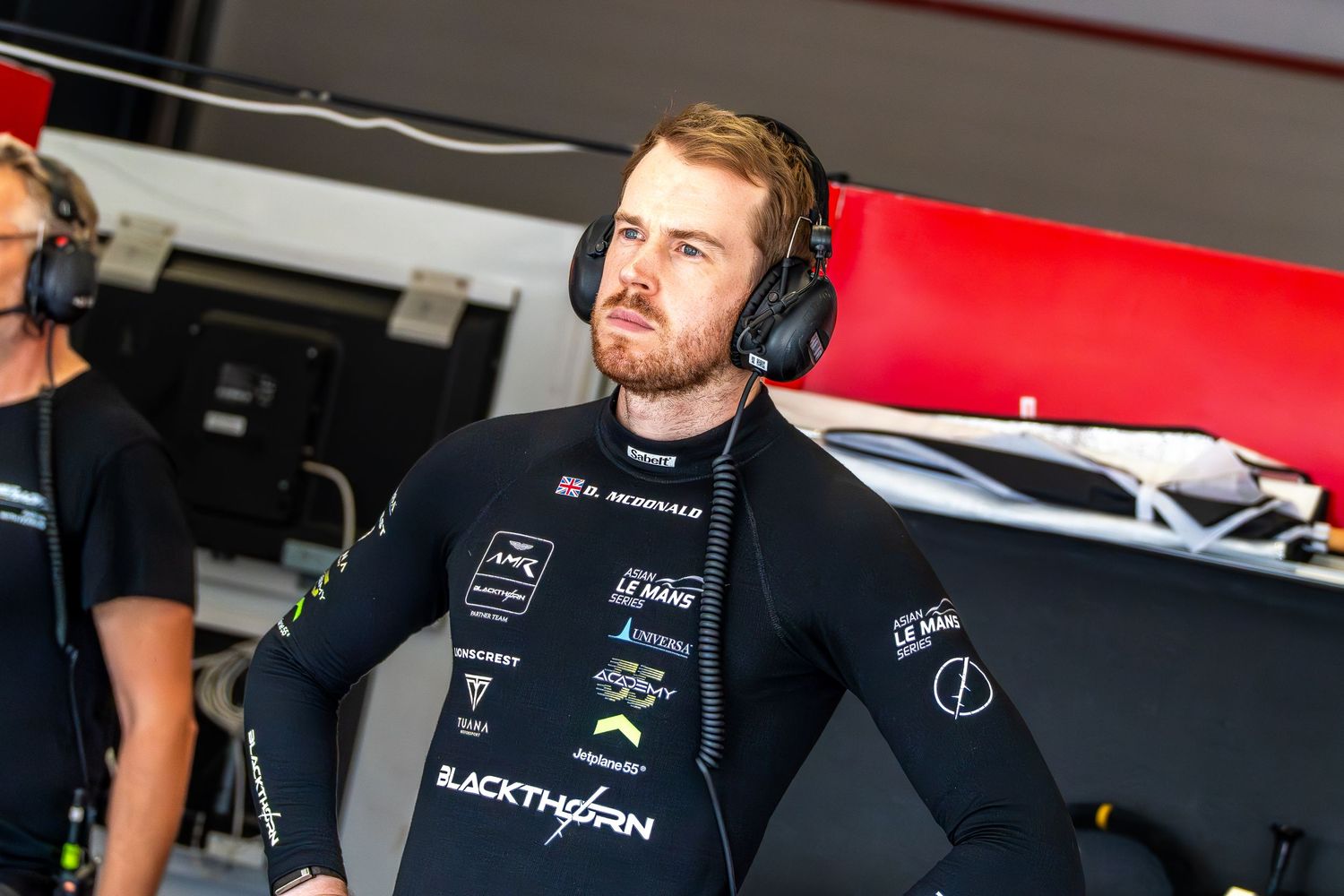 A racing driver wearing a headset sits inside the team garage during the event.