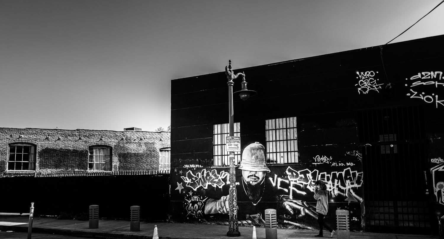 Black and white photo of a graffiti-covered urban building wall with street art murals in an industrial area.