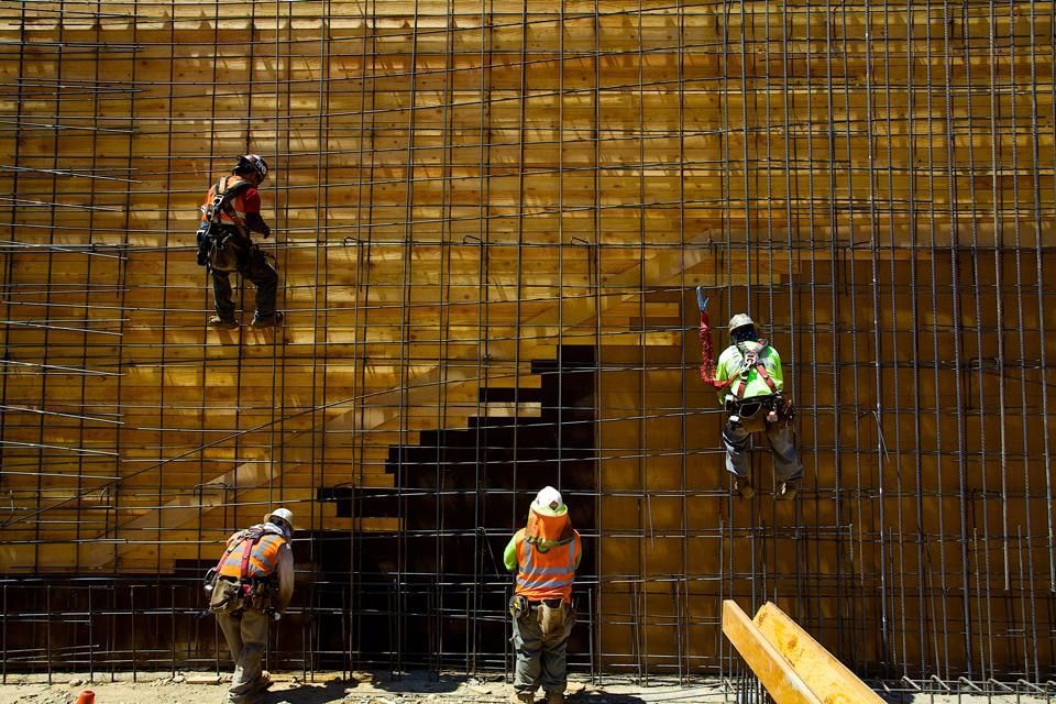 Construction worker in safety vest walking through a large concrete structure at a building site.