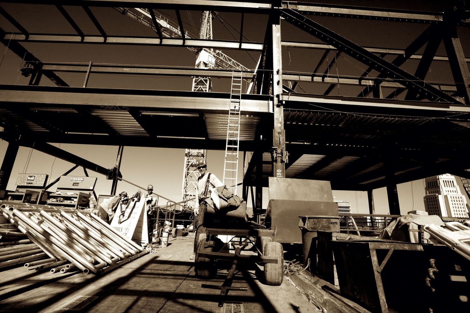 Sepia toned photo of a worker on heavy machinery inside an industrial warehouse.