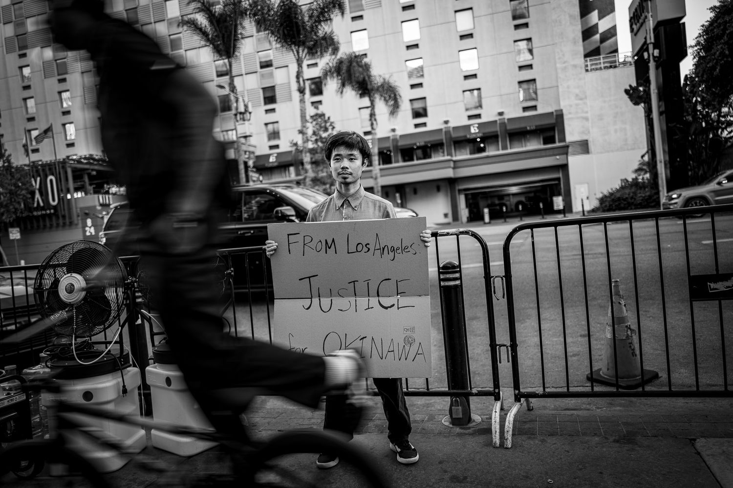 Black and white photo of a person holding a Justice sign from Los Angeles at an outdoor protest.