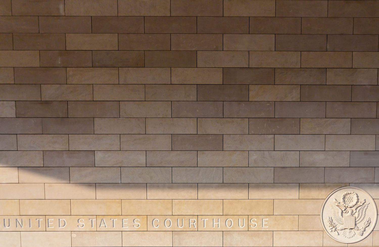 Exterior brick wall of a United States Courthouse building with official seal emblem.