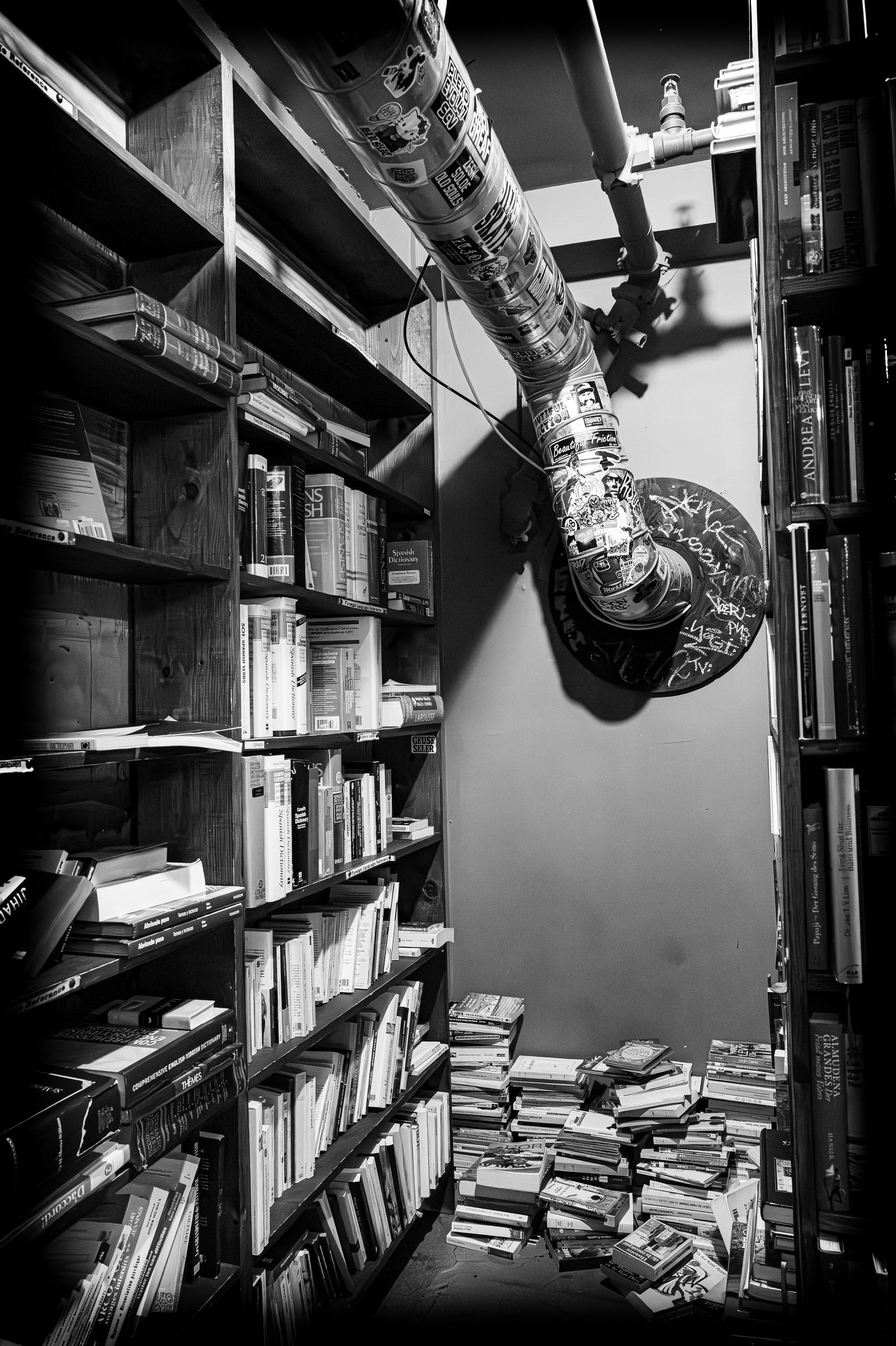 Black and white bookstore interior with shelves and sticker-covered pole.