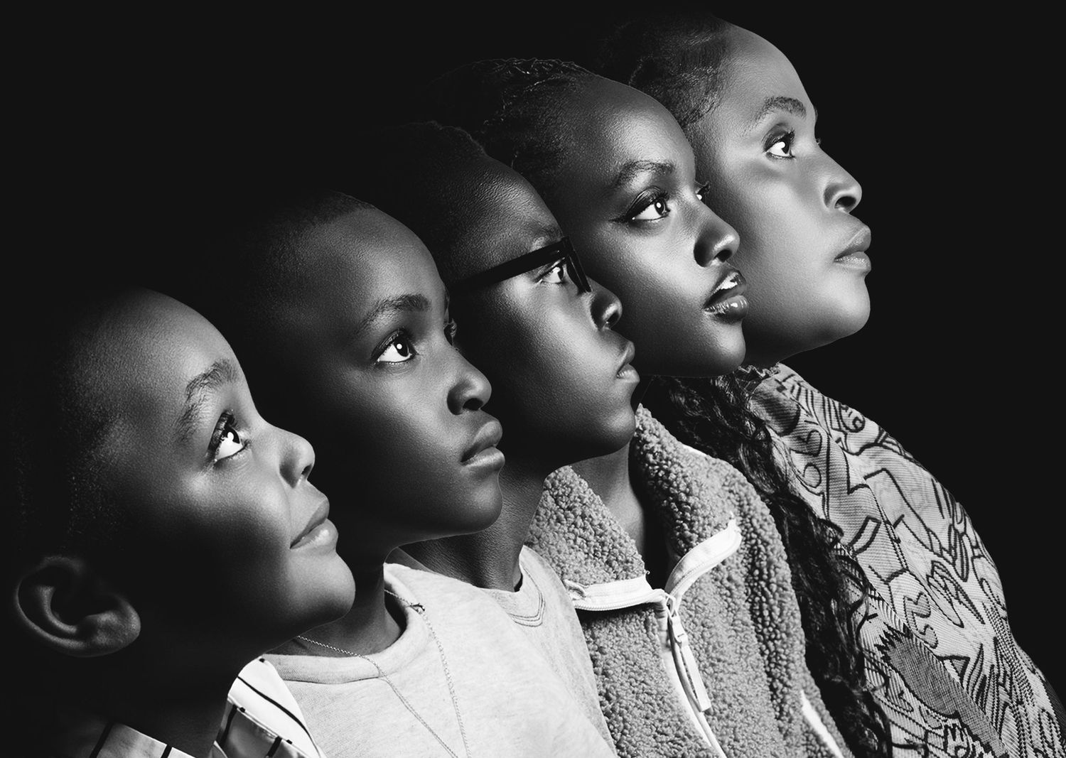 Black and white portrait of four African children looking upward in a dramatic, artistic composition.