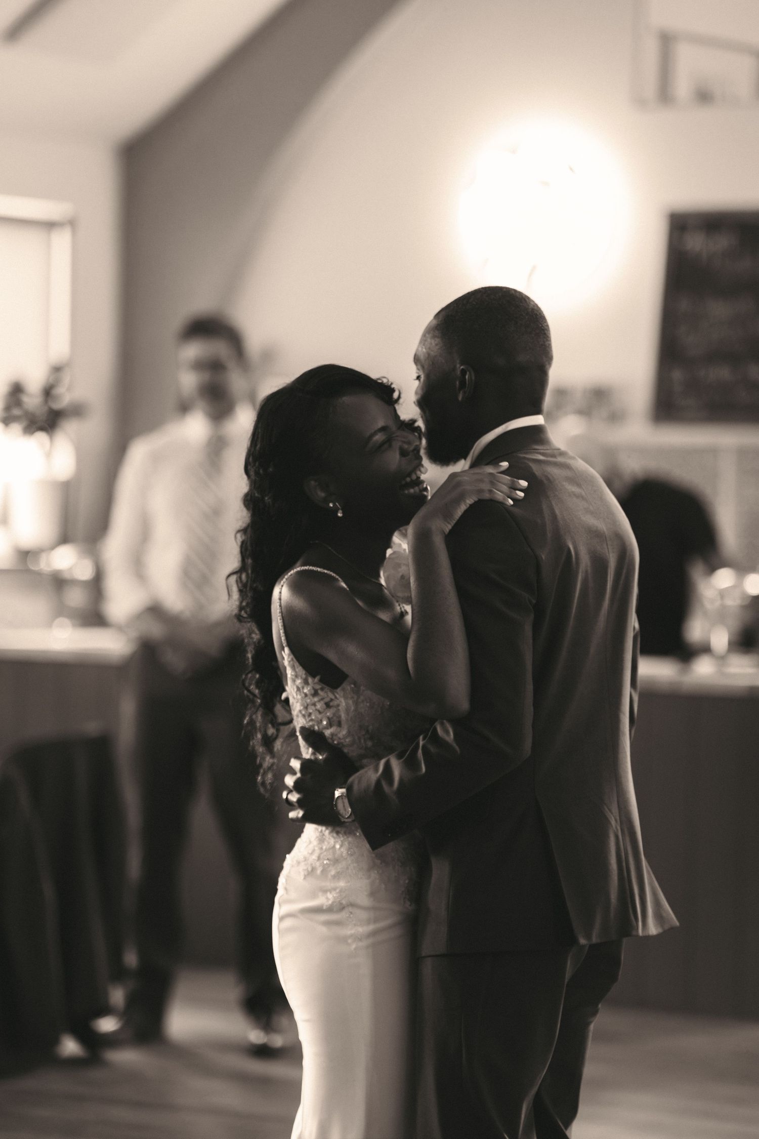 Black and white photo of a bride and groom sharing their first dance at a wedding reception.