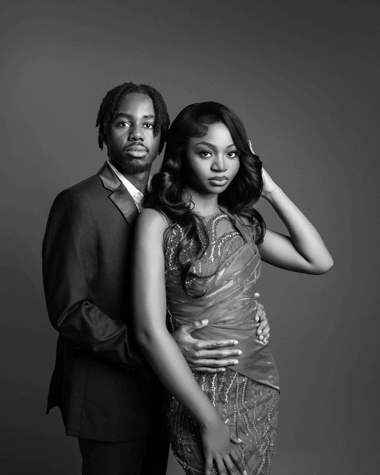 Black and white studio portrait of an elegant couple in formal attire posing together.