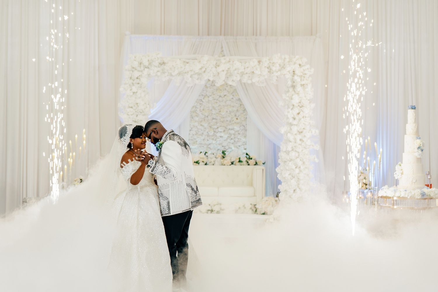 Bride and groom share intimate first dance moment in cloud of fog at all-white wedding reception.