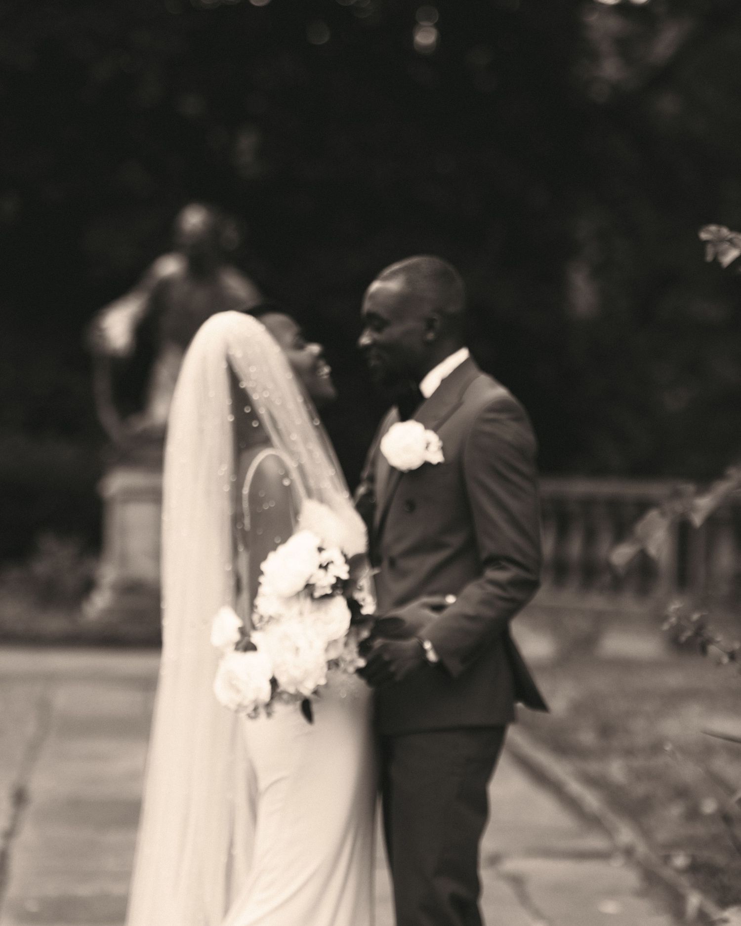 A bride and groom share a romantic moment in a black and white outdoor wedding portrait.