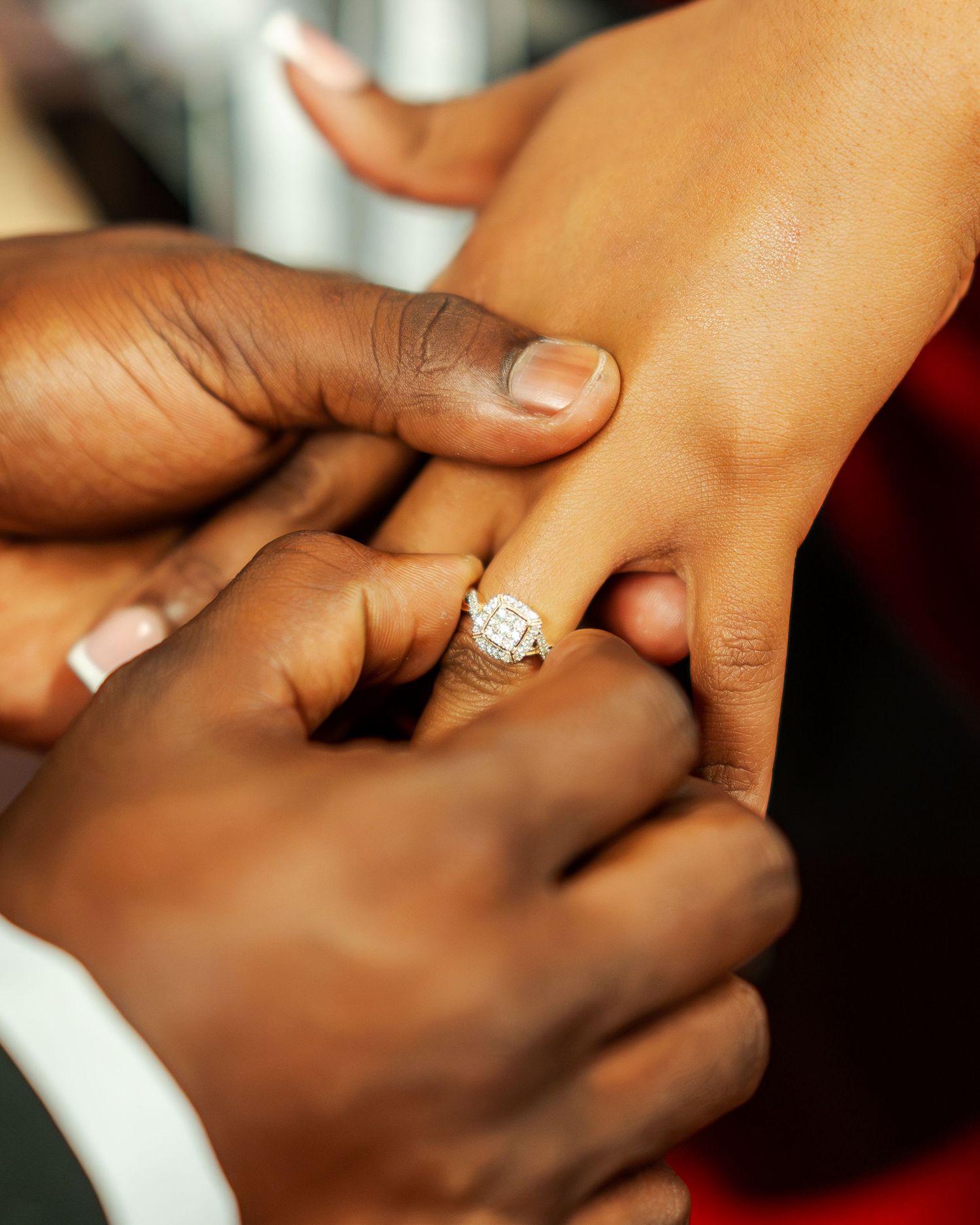 Close-up of a diamond engagement ring being placed on a woman's finger during a proposal.