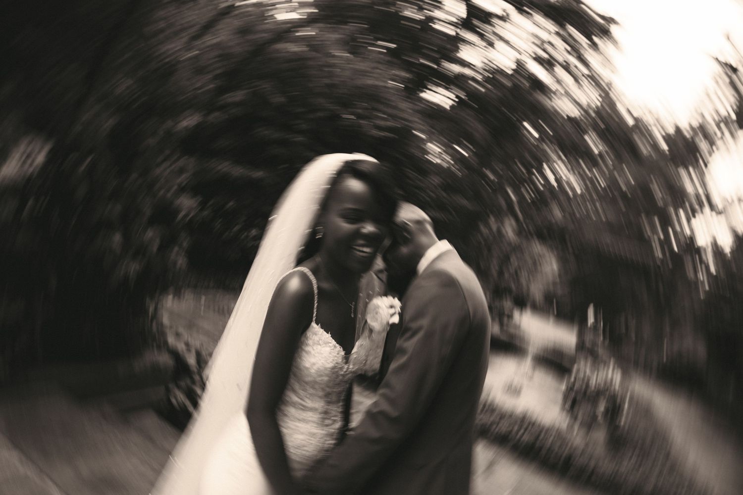 Bride and groom embracing outdoors in artistic swirl effect black and white wedding photo.