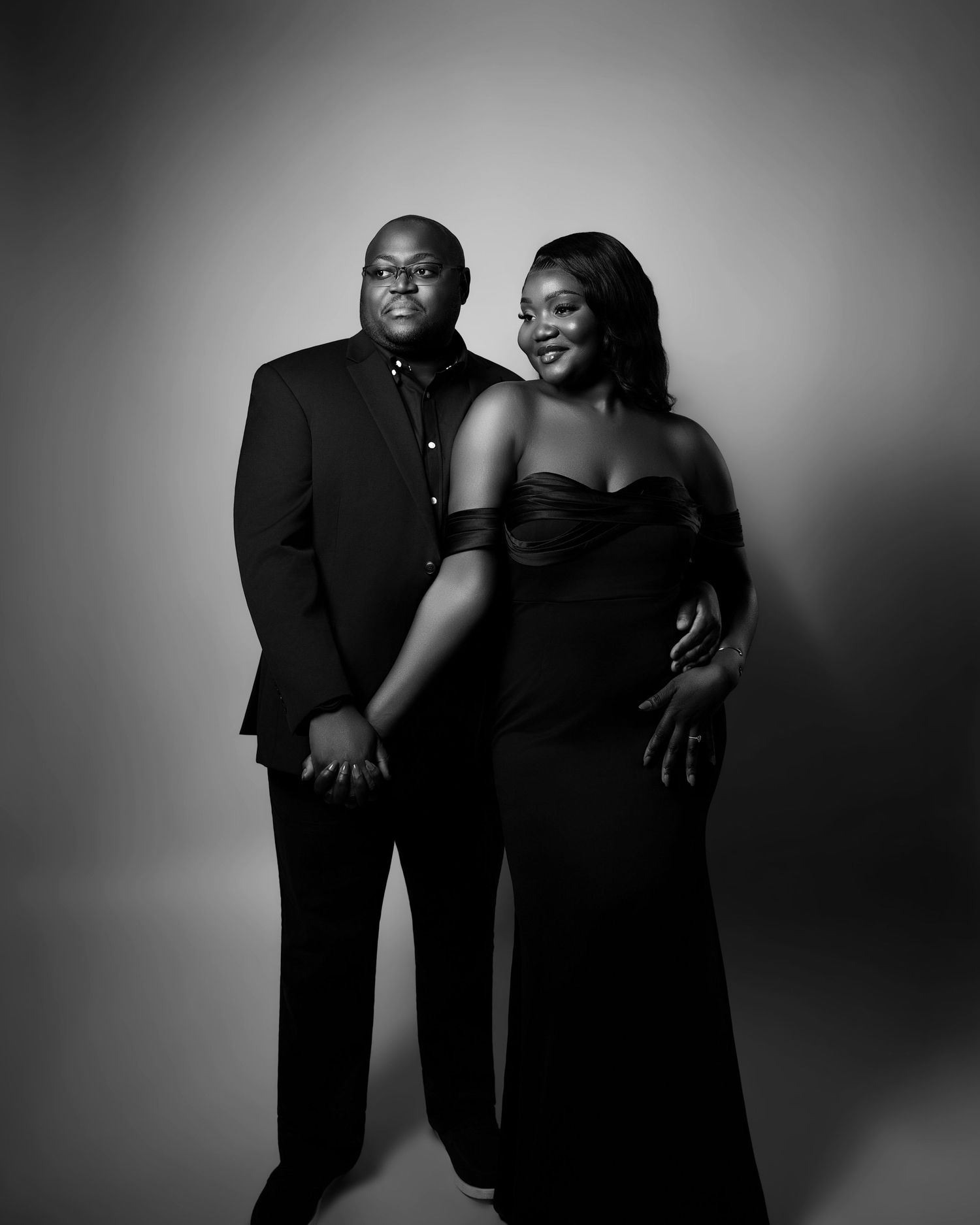 Elegant black and white portrait of couple in formal black attire posing together for engagement photo.