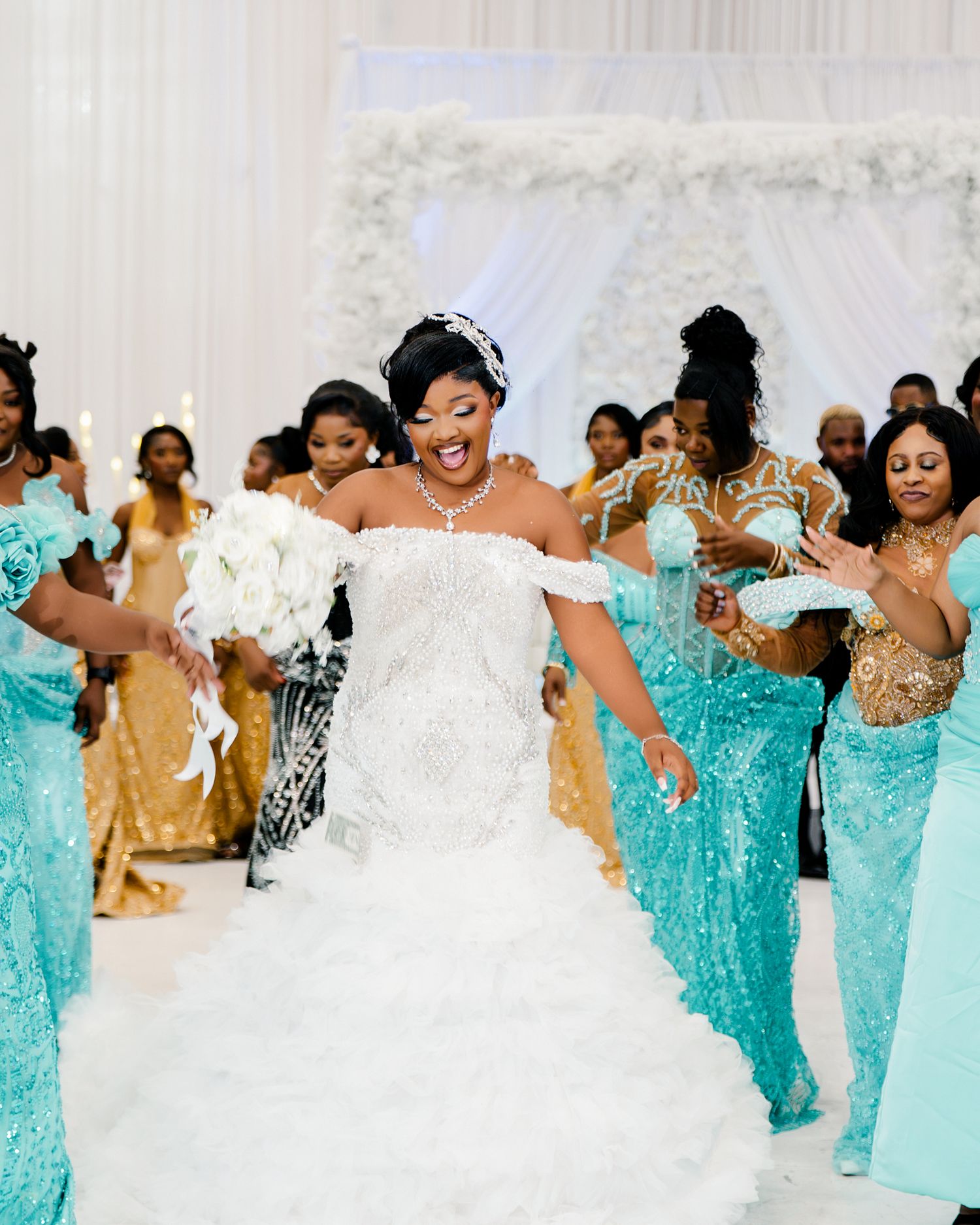 Bride in ruffled white gown celebrates with bridesmaids in teal sequin dresses at wedding reception.