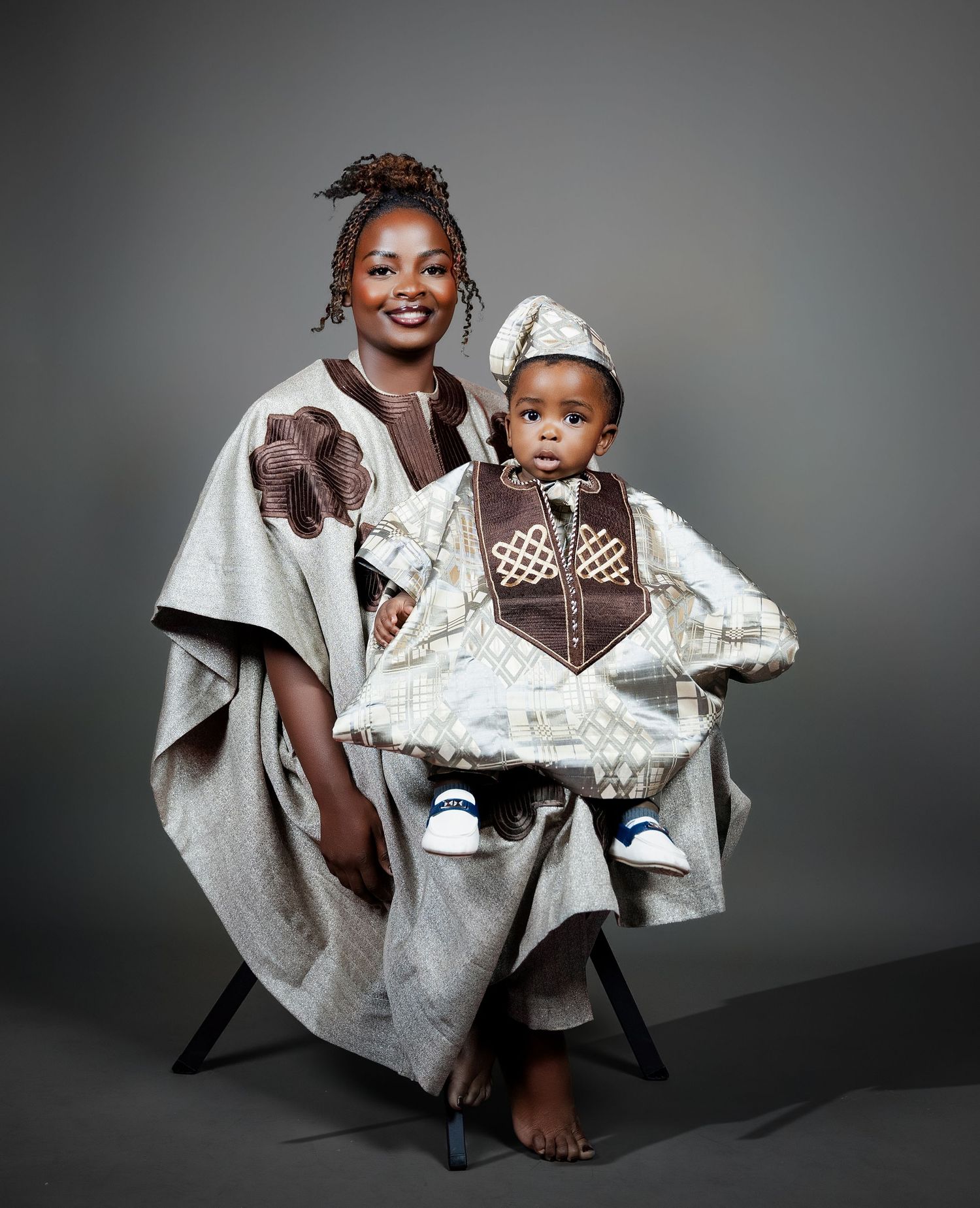 A smiling mother and baby dressed in matching traditional African attire during a cultural portrait session.