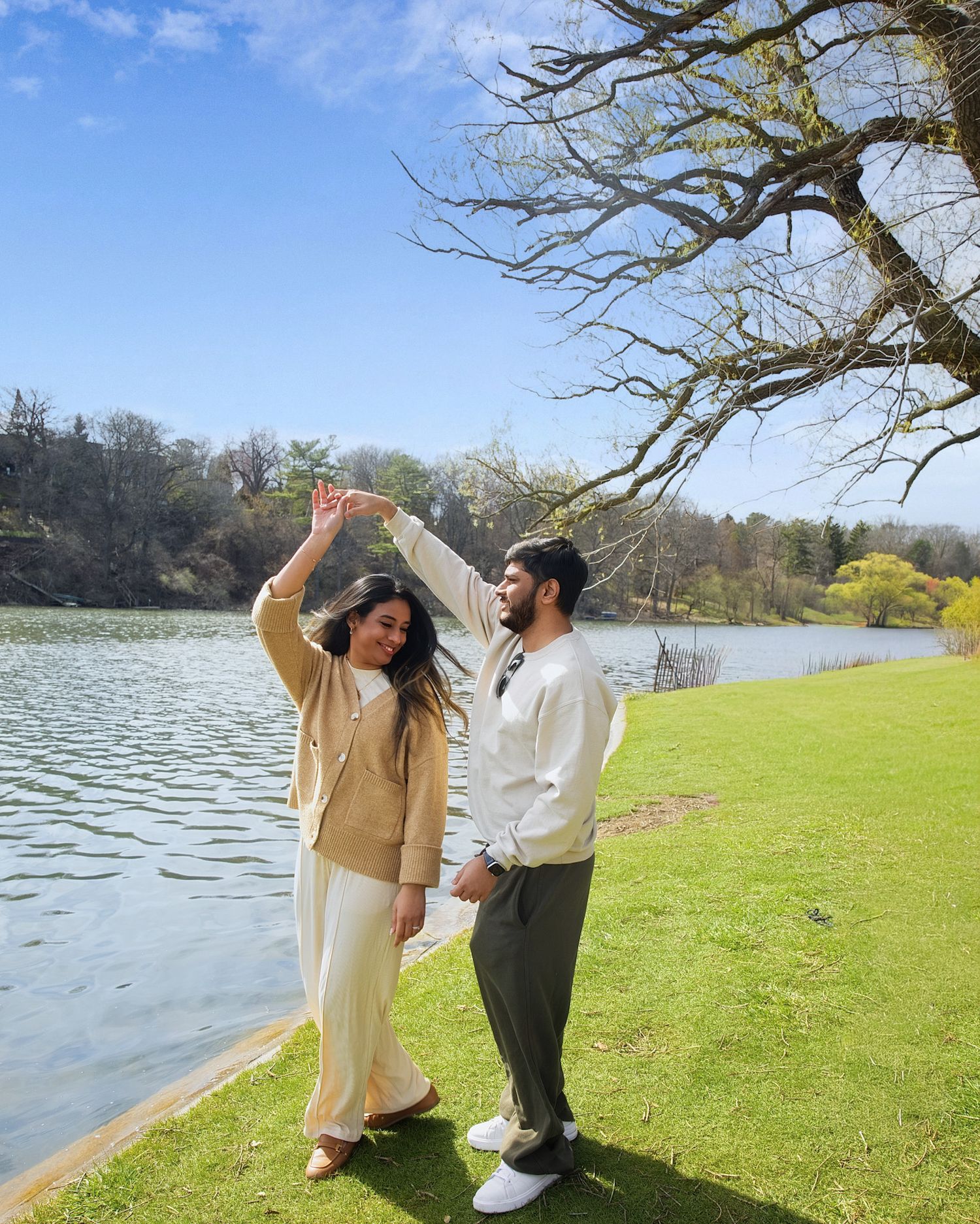 Couple dancing in a sunny day, surrounded by lush green grass and bare trees posted in a page for toronto photoshoot price range