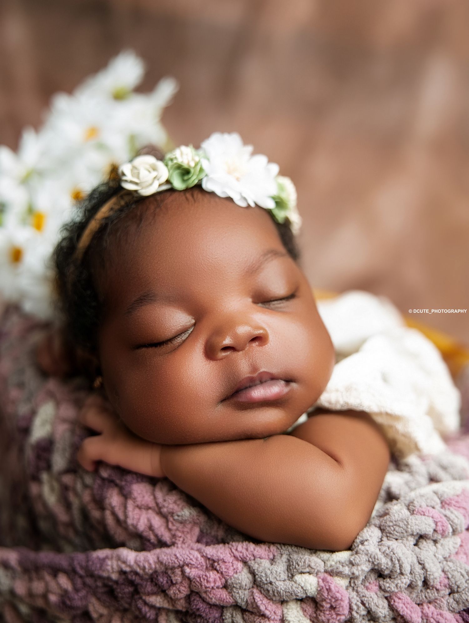 Close-up of sleeping newborn baby with floral headband resting on knit blanket with daisies shot by a Toronto newborn photographer