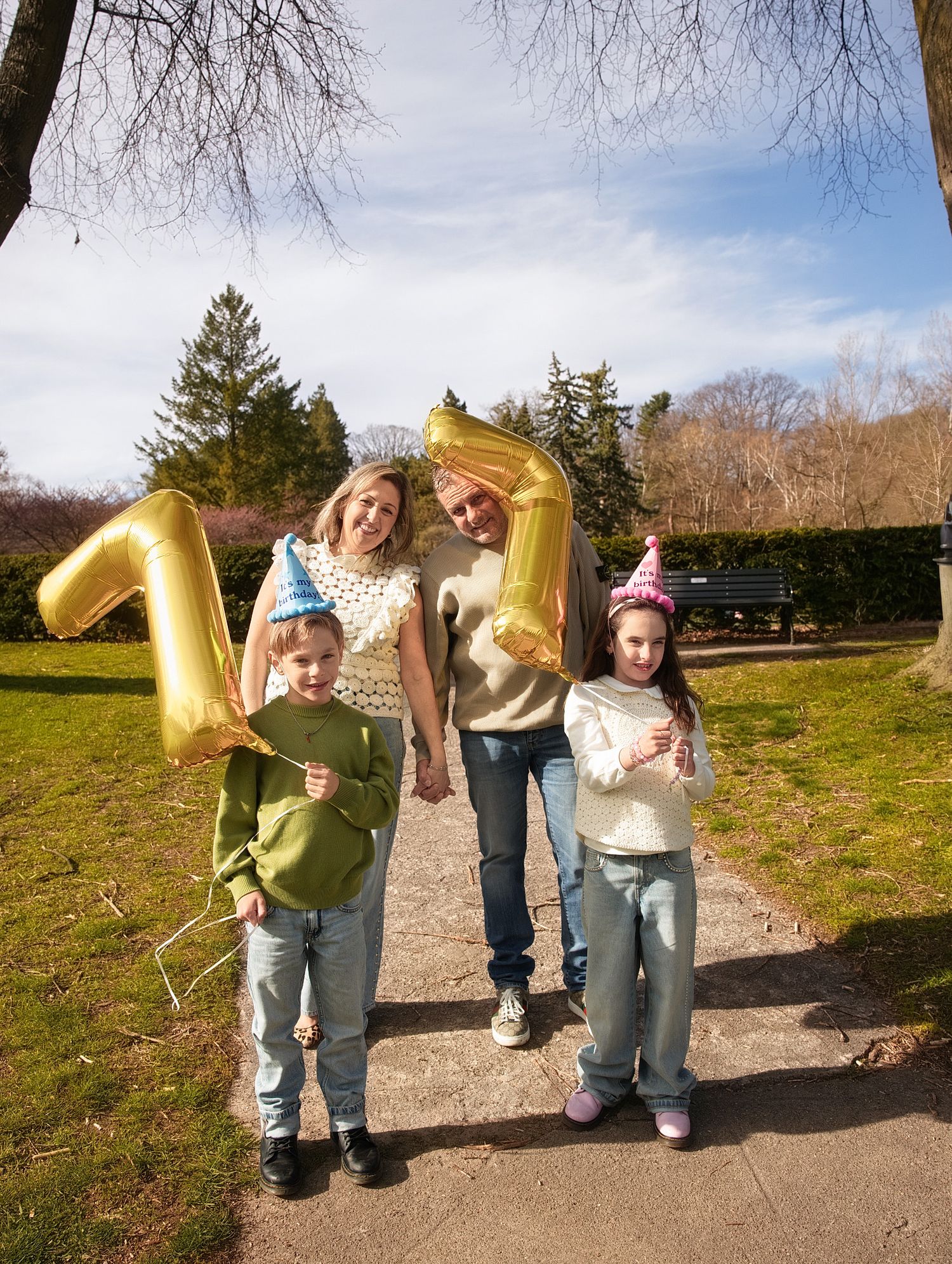 Family photography in Downtown Toronto captures Joyful family celebrating with gold number balloon outdoors in a park