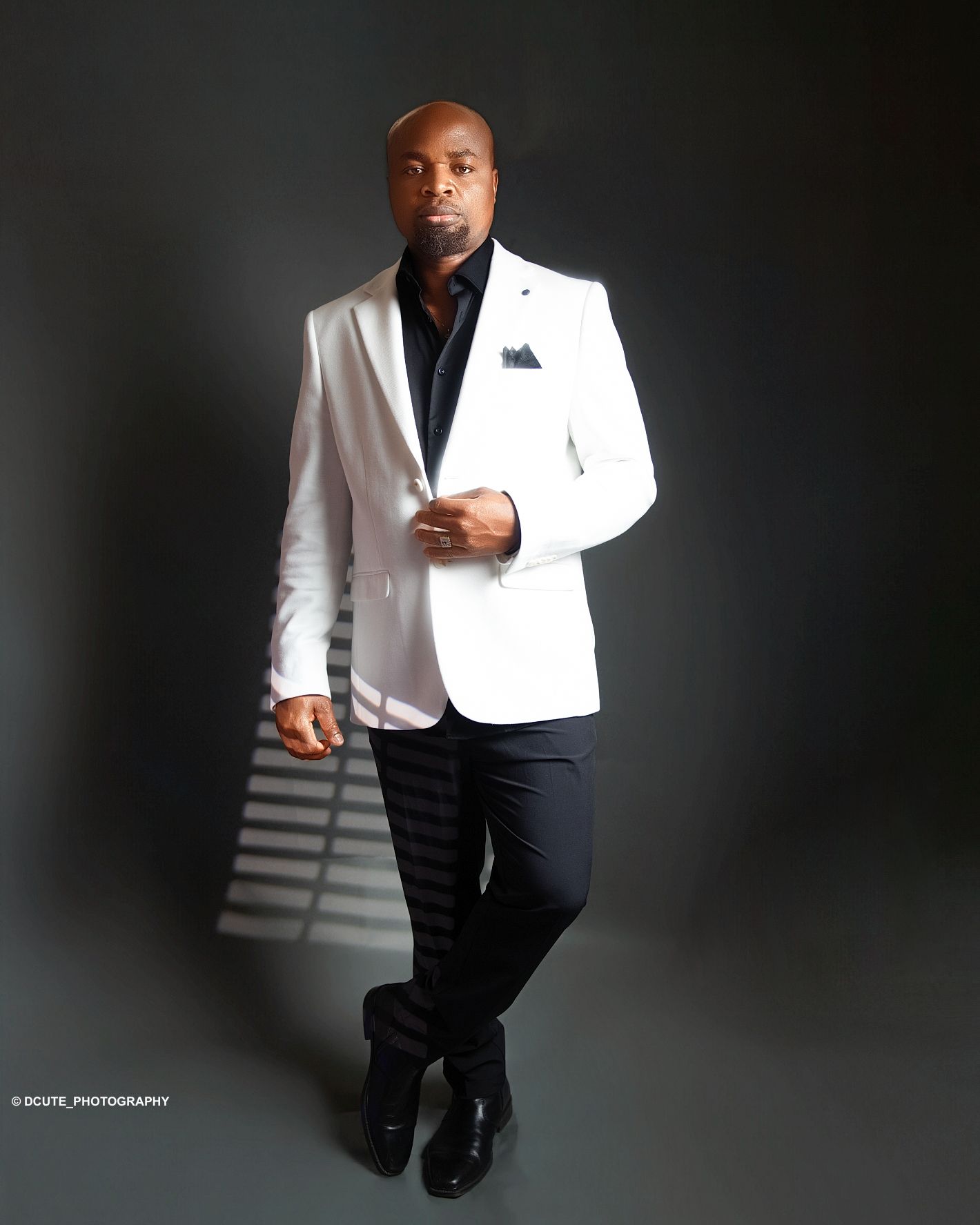 Stylish man in white blazer and black pants posing confidently in professional studio photography in toronto