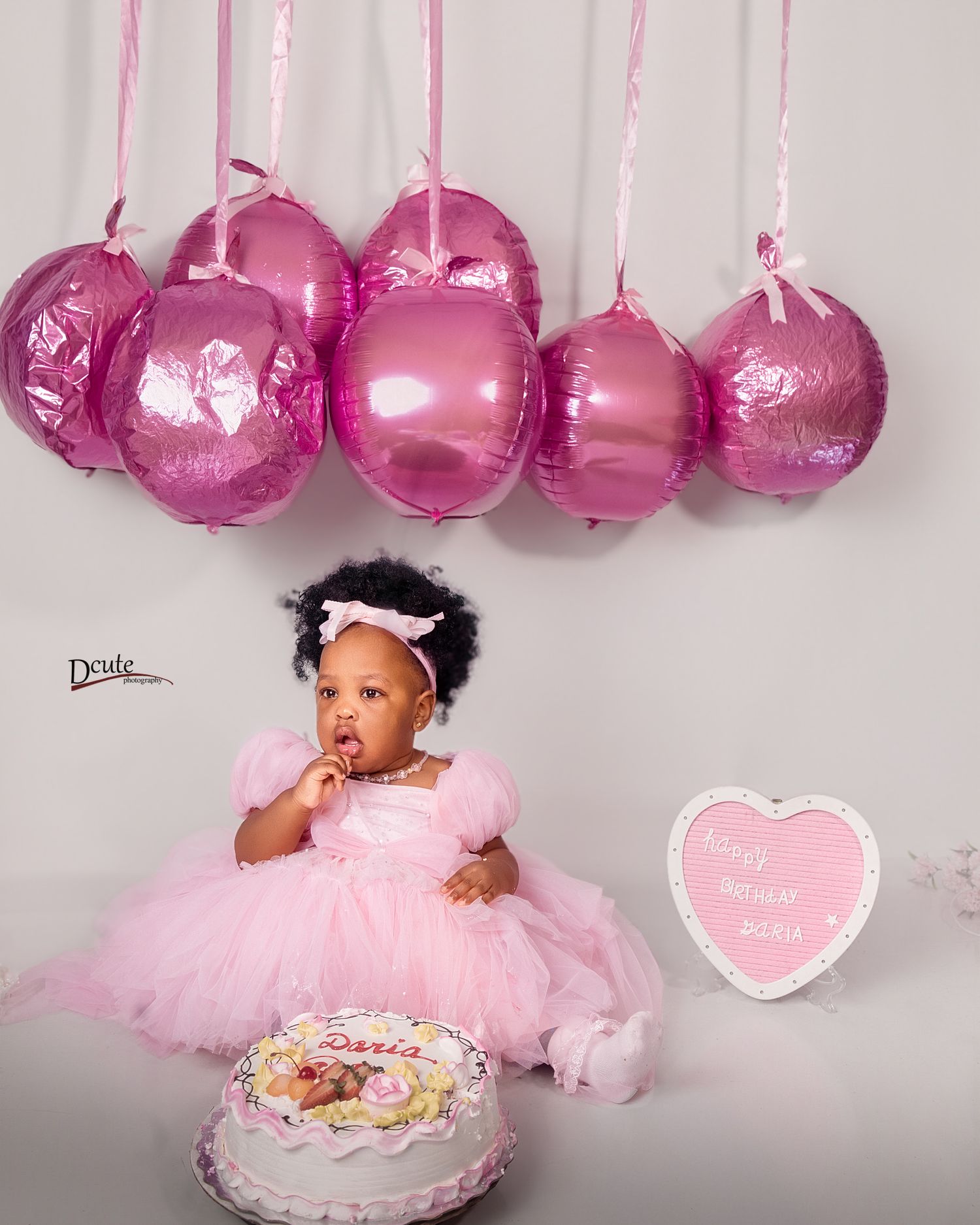 Toronto family photographer photographing parents with their children in Toronto, cake and pink balloons at a studio photoshoot.
