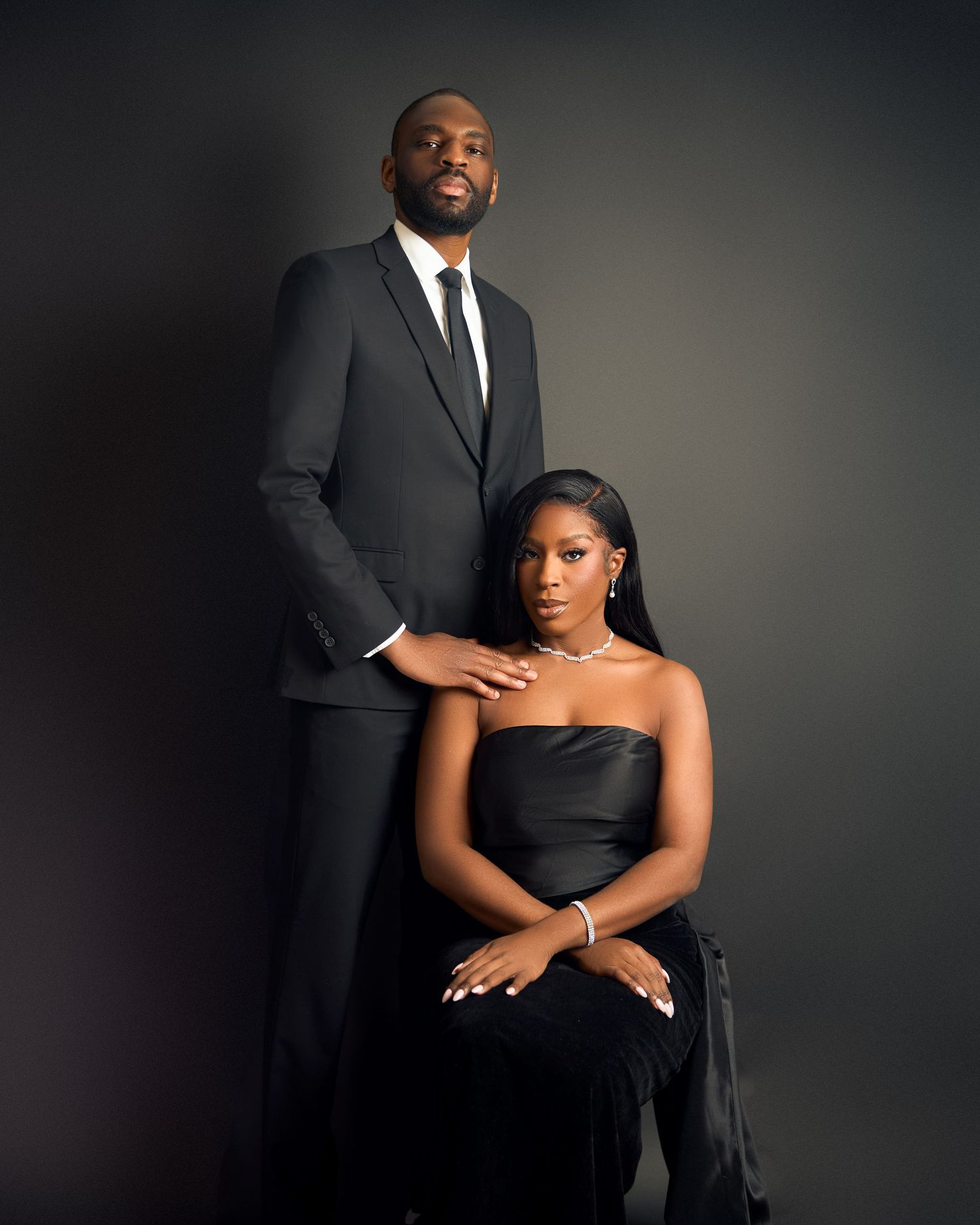 Couple in elegant black formal outfits posing in a professional studio portrait setting in toronto
