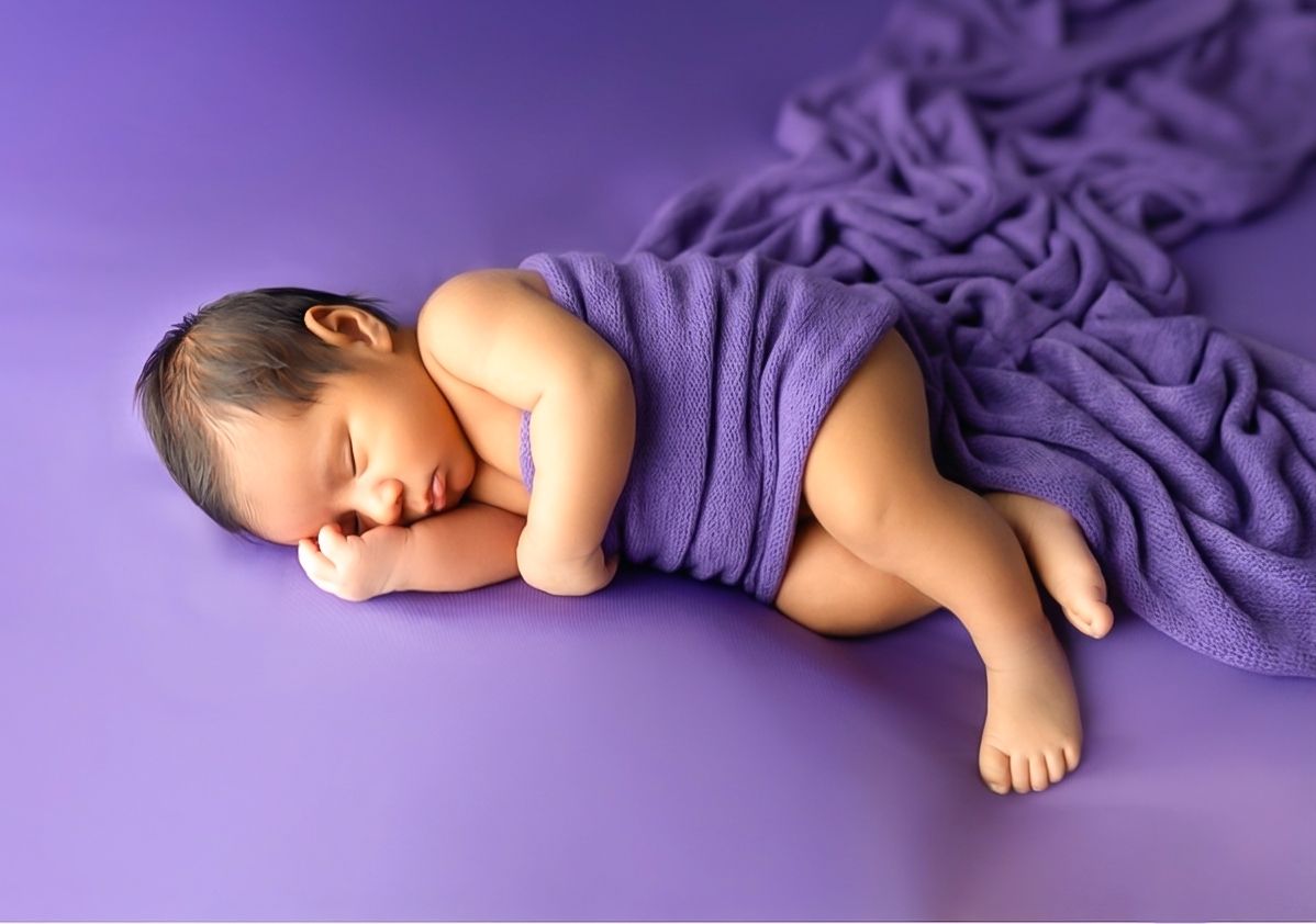 Sleeping newborn baby in Newborn photography in Toronto with parents wrapped in purple blanket on matching purple studio