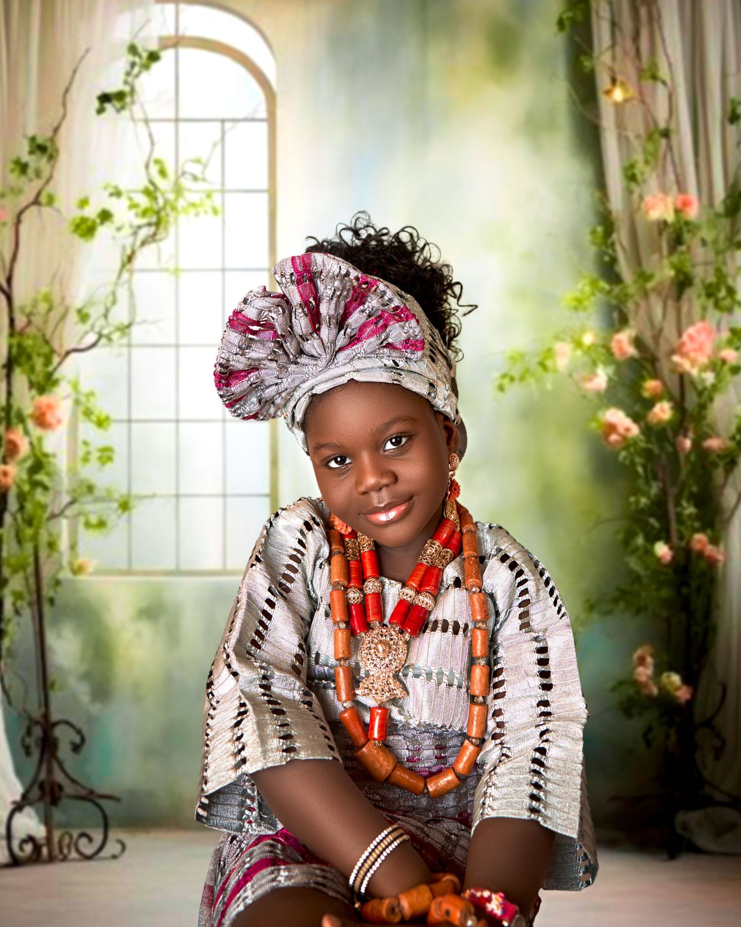 Young girl in traditional African attire with colorful beaded jewelry and head wrap poses gracefully.