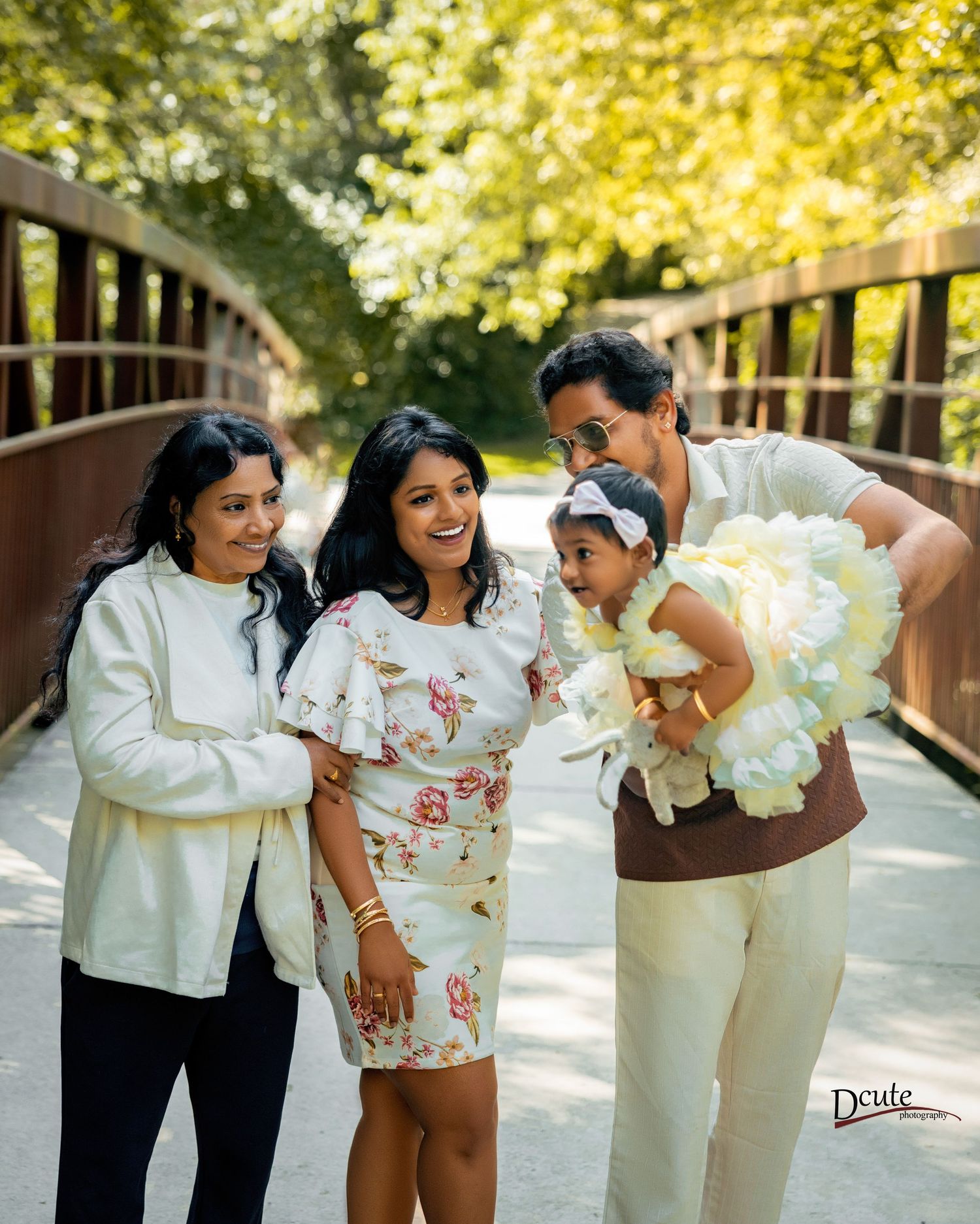 Indian family of four posing on bridge in park with baby in white tutu dress during an outdoor family portrait session in downtown toronto