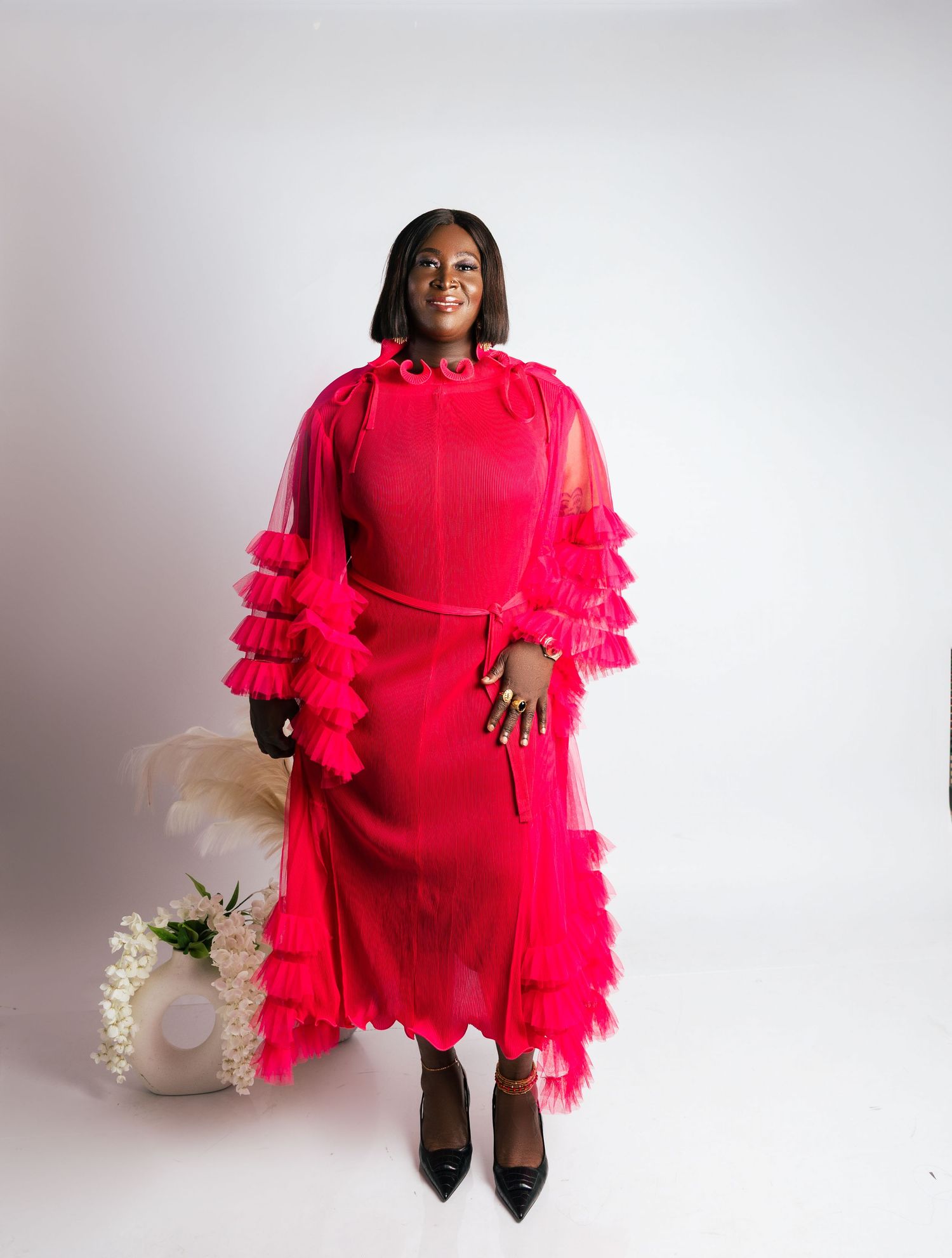 Woman in vibrant red ruffled tulle midi dress with layered sleeves in studio setting in relaxed outdoor birthday photos toronto