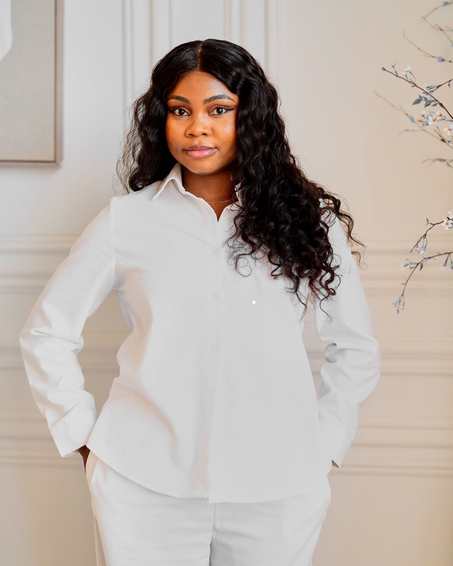 Woman in white button-down shirt posing confidently in elegant white interior setting as a maternity photographer in toronto