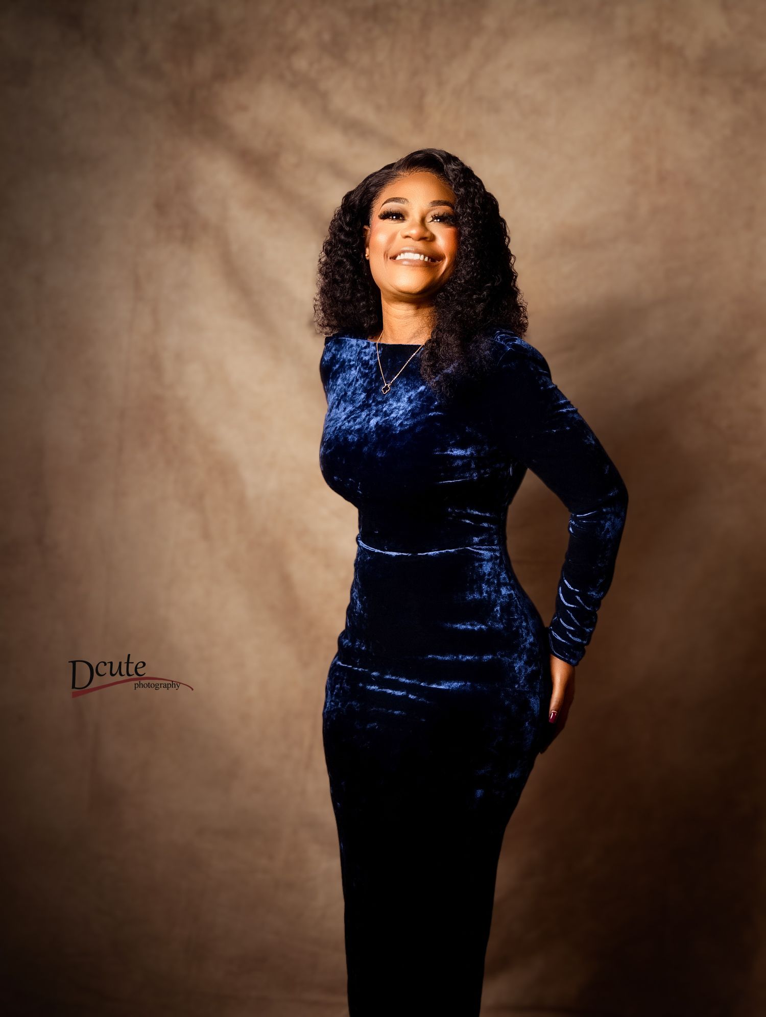 Woman in blue velvet dress smiling in professional studio portrait photography.