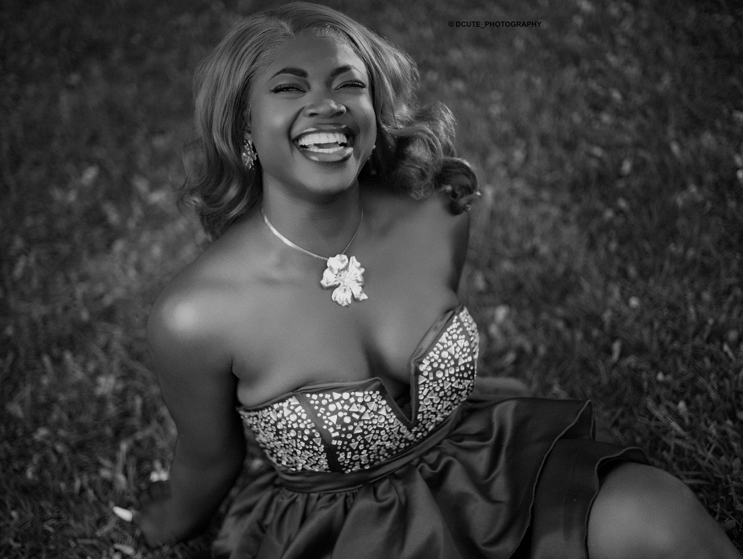 Black and white image of laughing woman in embellished strapless dress sitting outdoors unique birthday photoshoot toronto