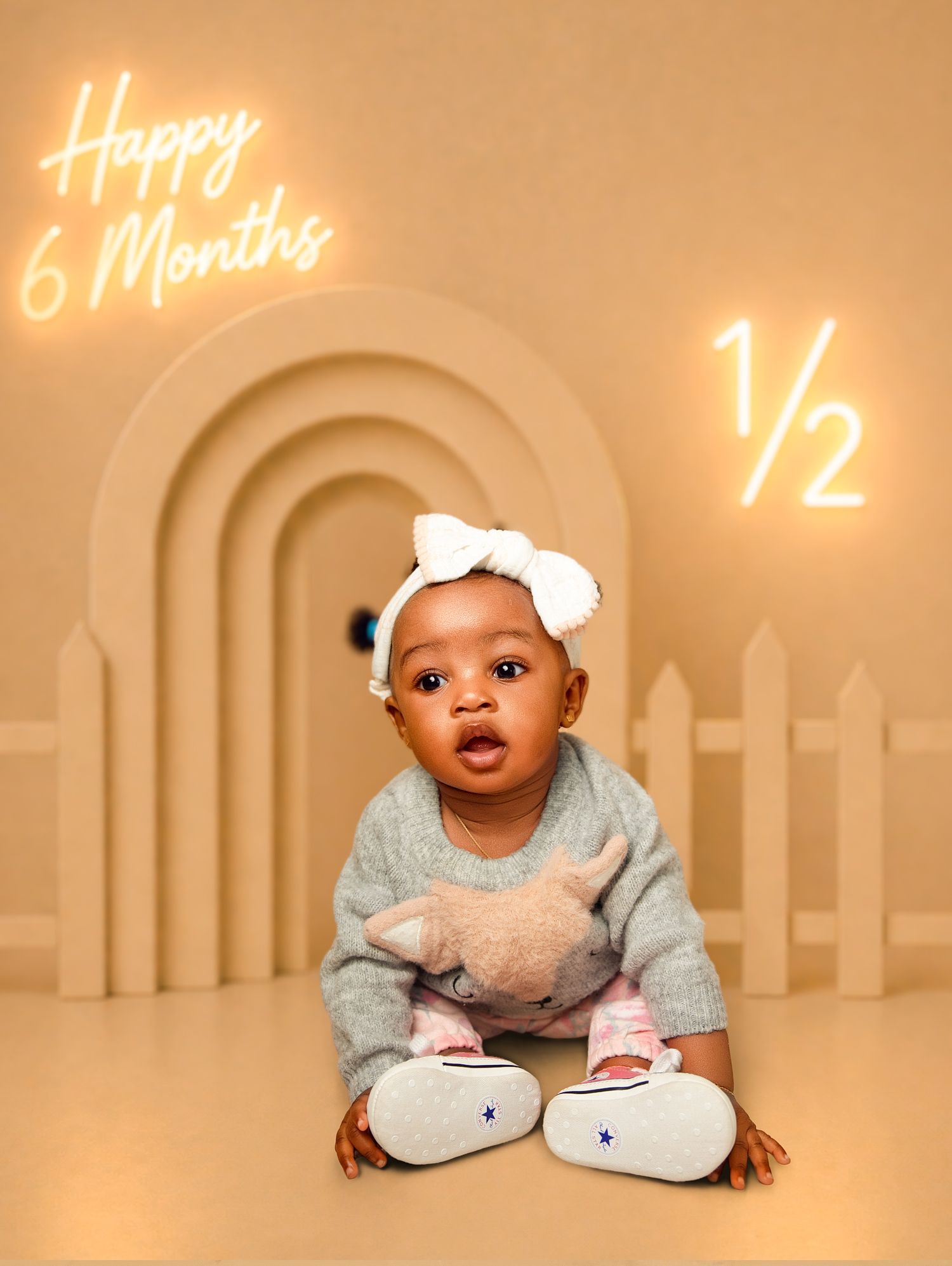 Baby girl celebrates 6 months milestone with neon signs and arch backdrop.
