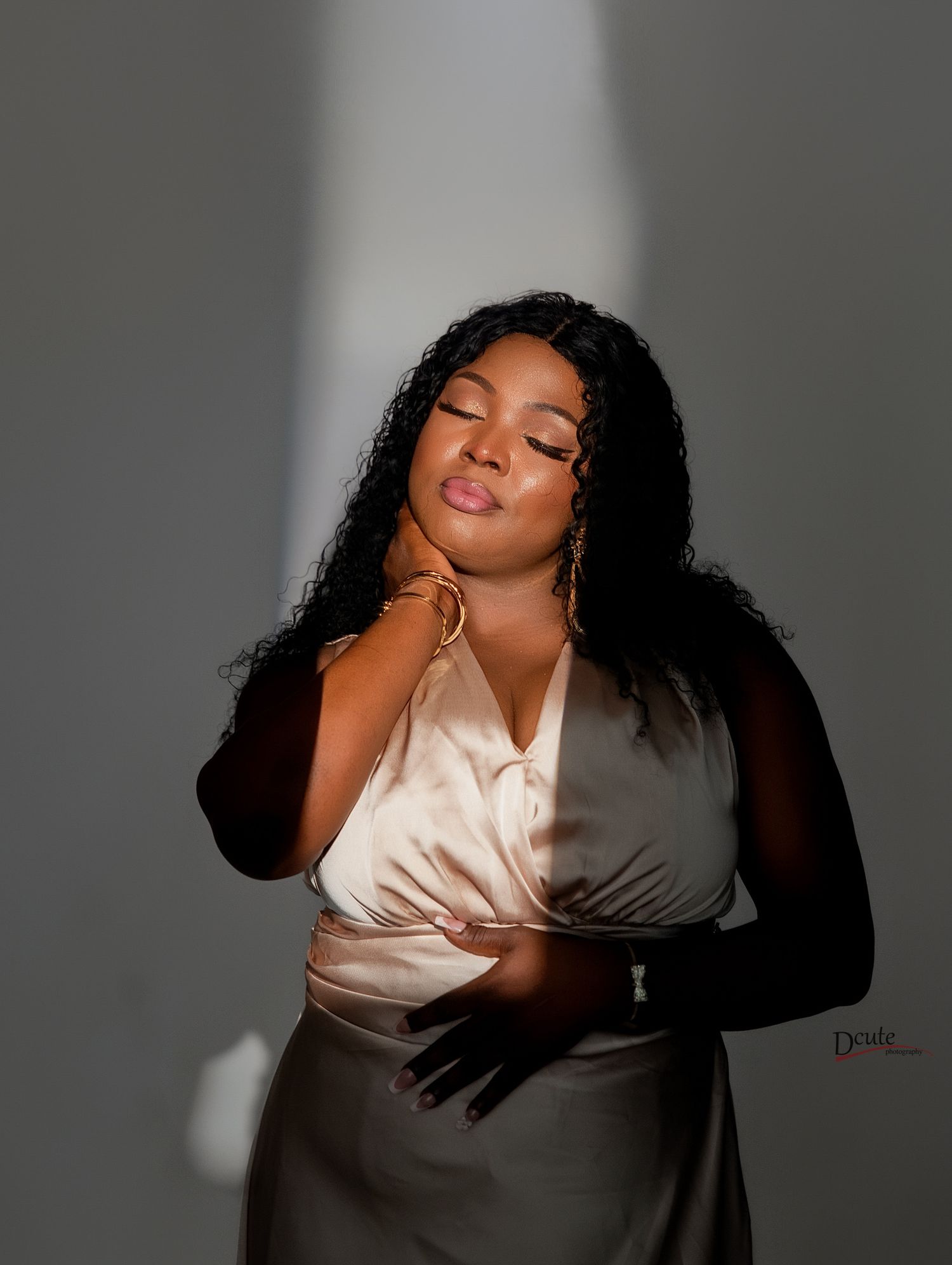 A woman in a satin wrap top poses gracefully with eyes closed in dramatic studio lighting. Family Fine art photography in toronto