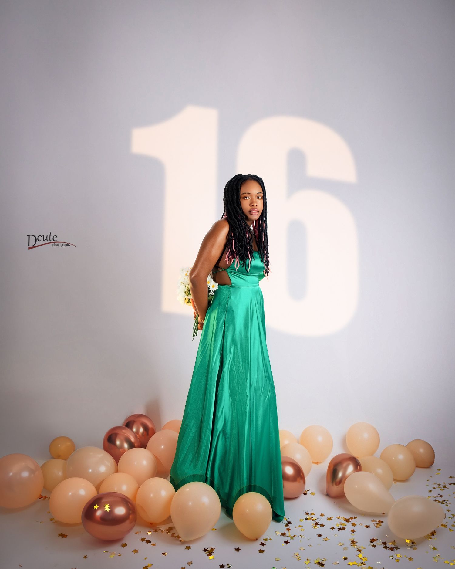 Teen girl in green satin gown poses at 16th birthday photoshoot in toronto with balloons and confetti.