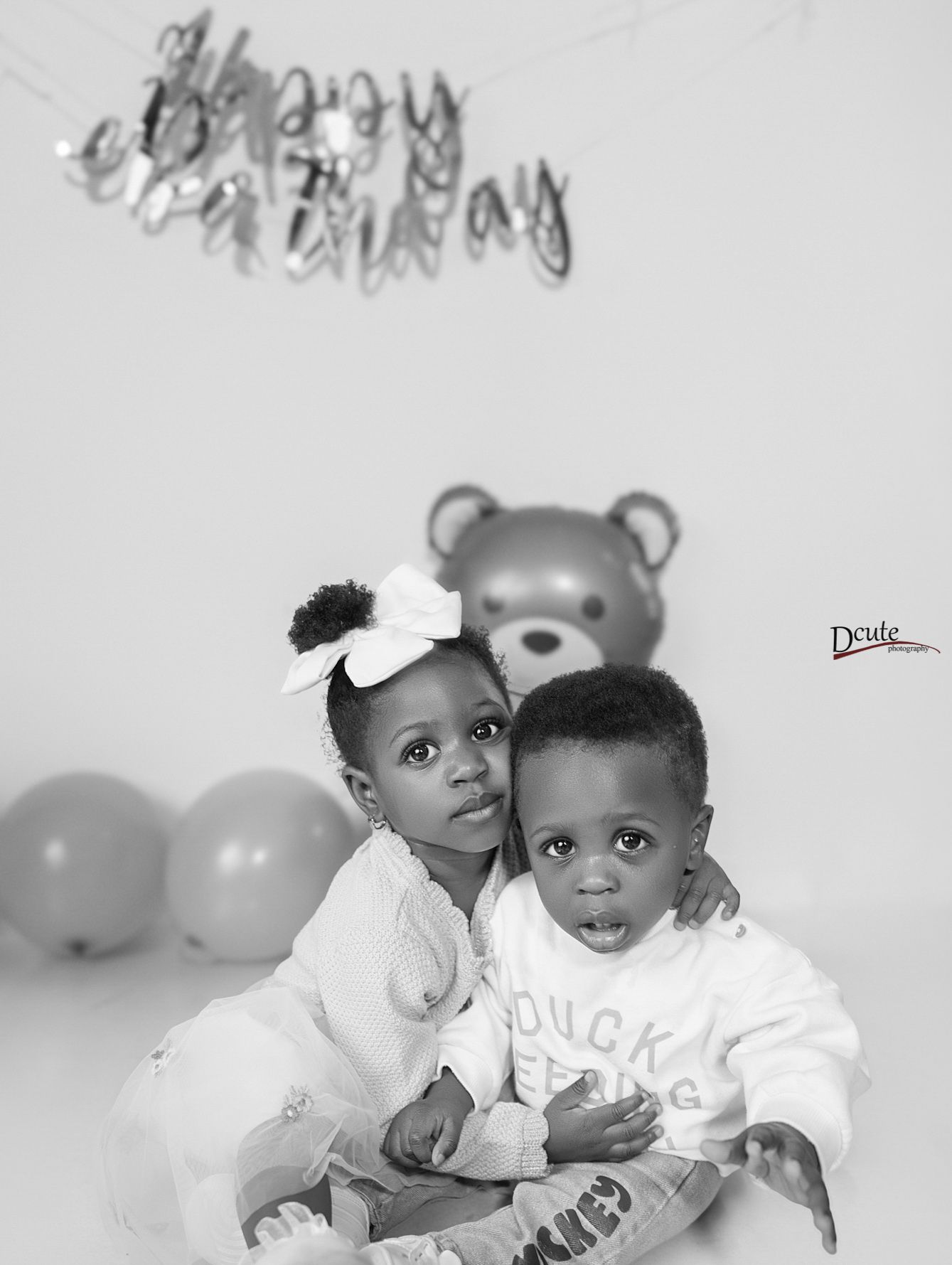 a Children’s photography in North York, feautres wo siblings sitting together outdoors under the trees in a studio