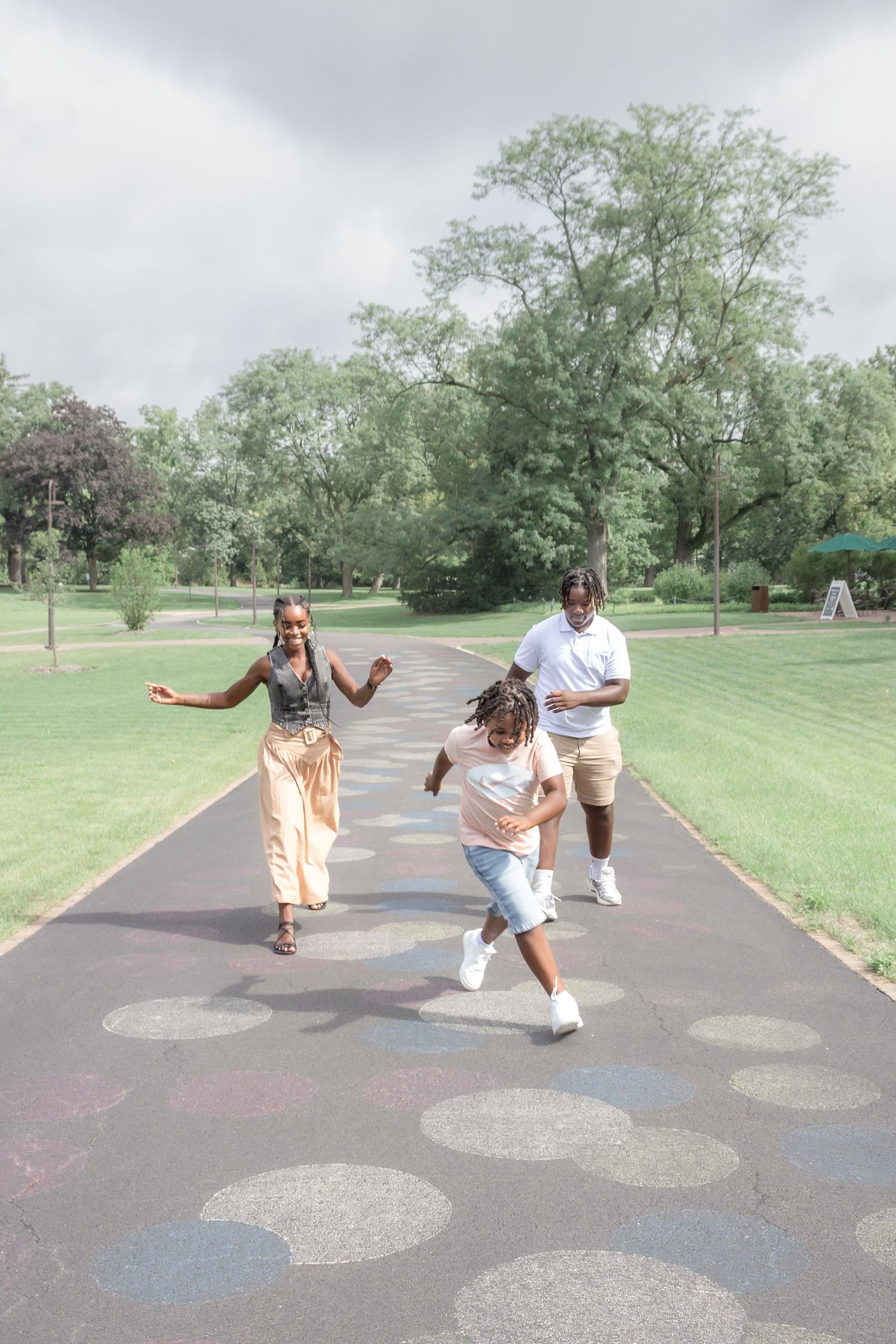 Family with two young children walking together along a park pathway during a natural outdoor family photography session.