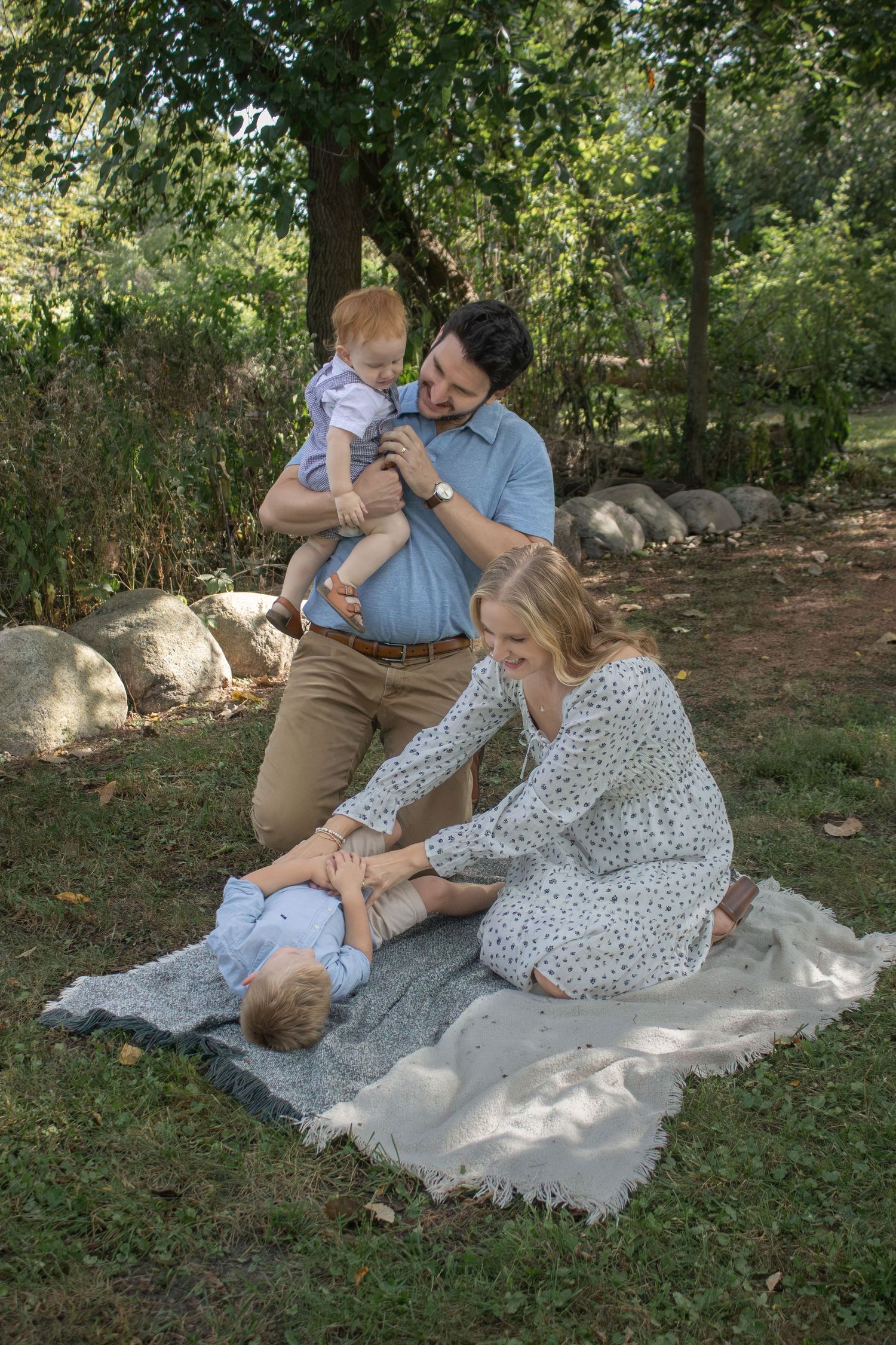 A happy family enjoys a relaxing outdoor picnic on a blanket in a sunlit green park.